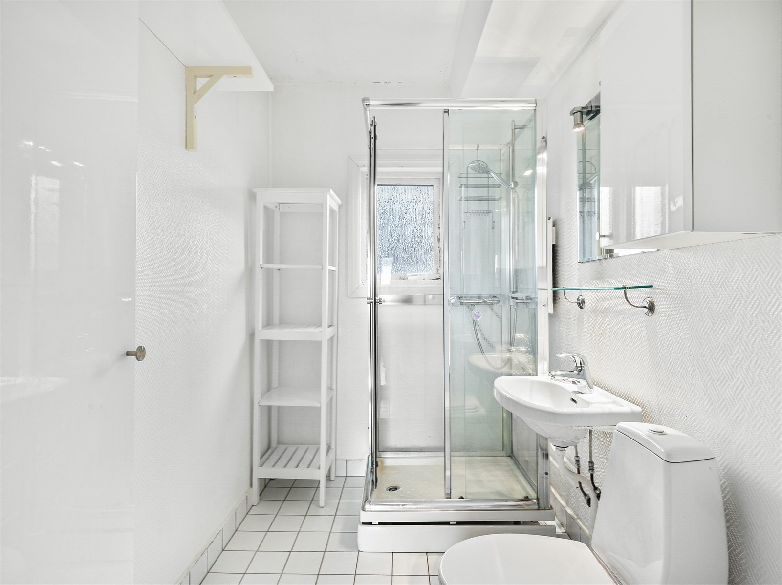 Fliser på gulv, malte strier på vegger og malt tak. Innredningen består av wc, dusjkabinett, servant, speil med overlys og opplegg for vaskemaskin. Galleribilde