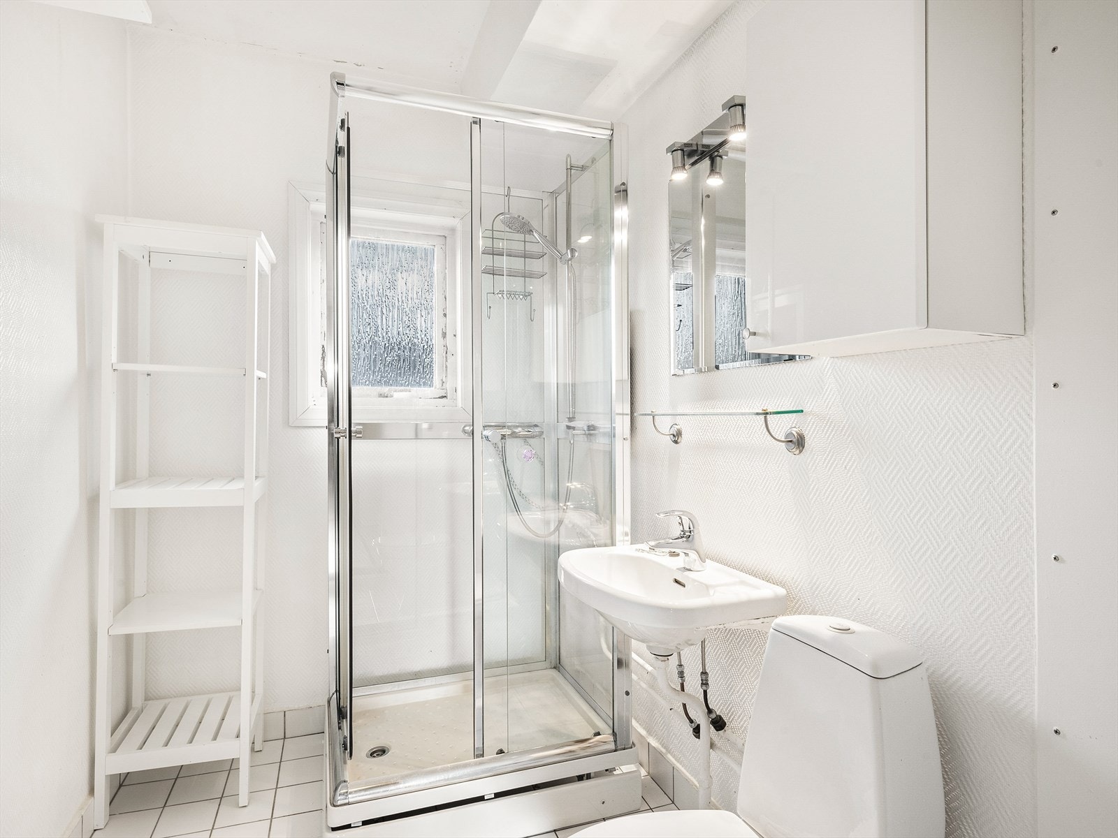Fliser på gulv, malte strier på vegger og malt tak. Innredningen består av wc, dusjkabinett, servant, speil med overlys og opplegg for vaskemaskin. Galleribilde