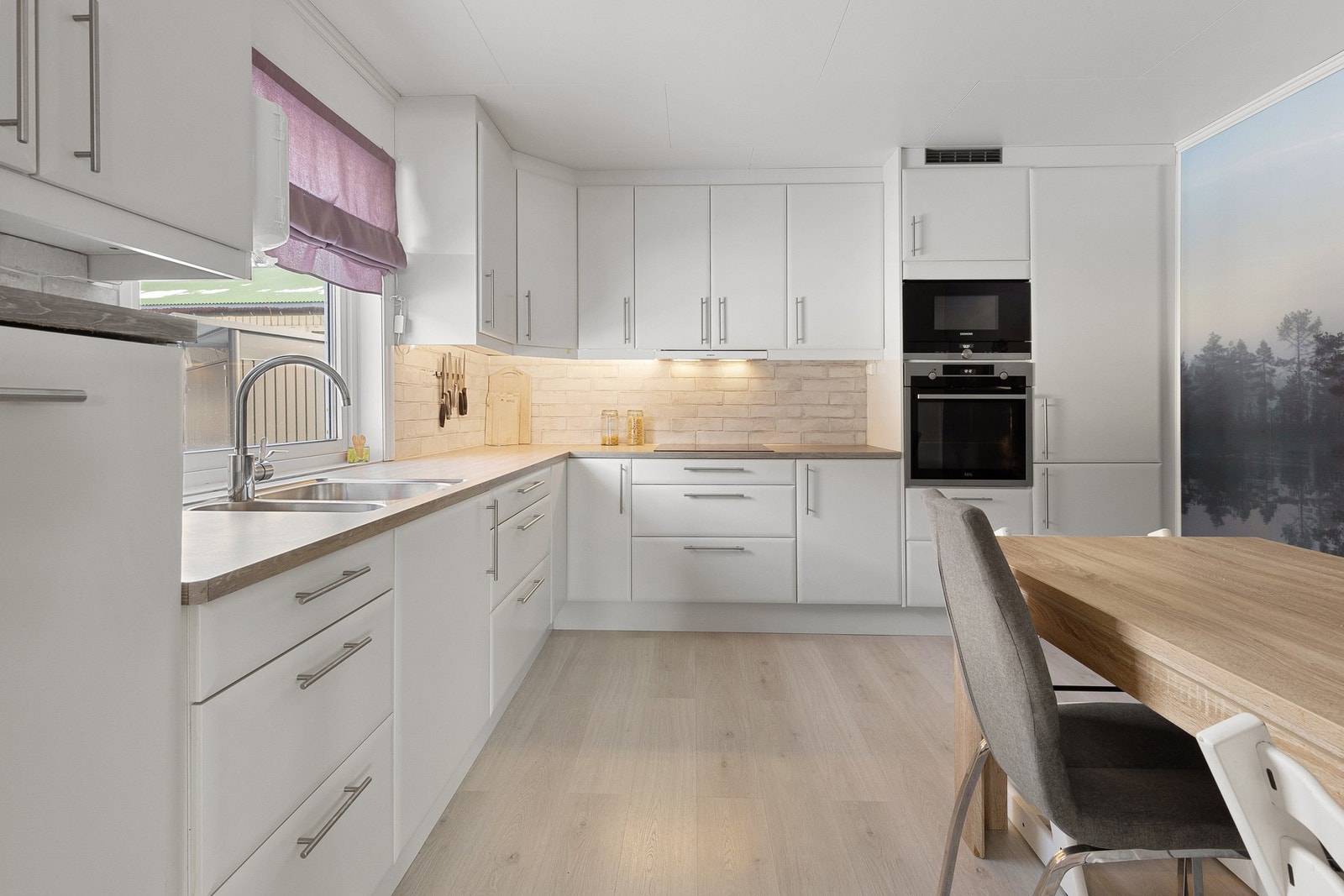 Pent og tidløst kjøkken som ble pusset opp i 2017. Hvite slette fronter og benkeplate av laminat. Galleribilde