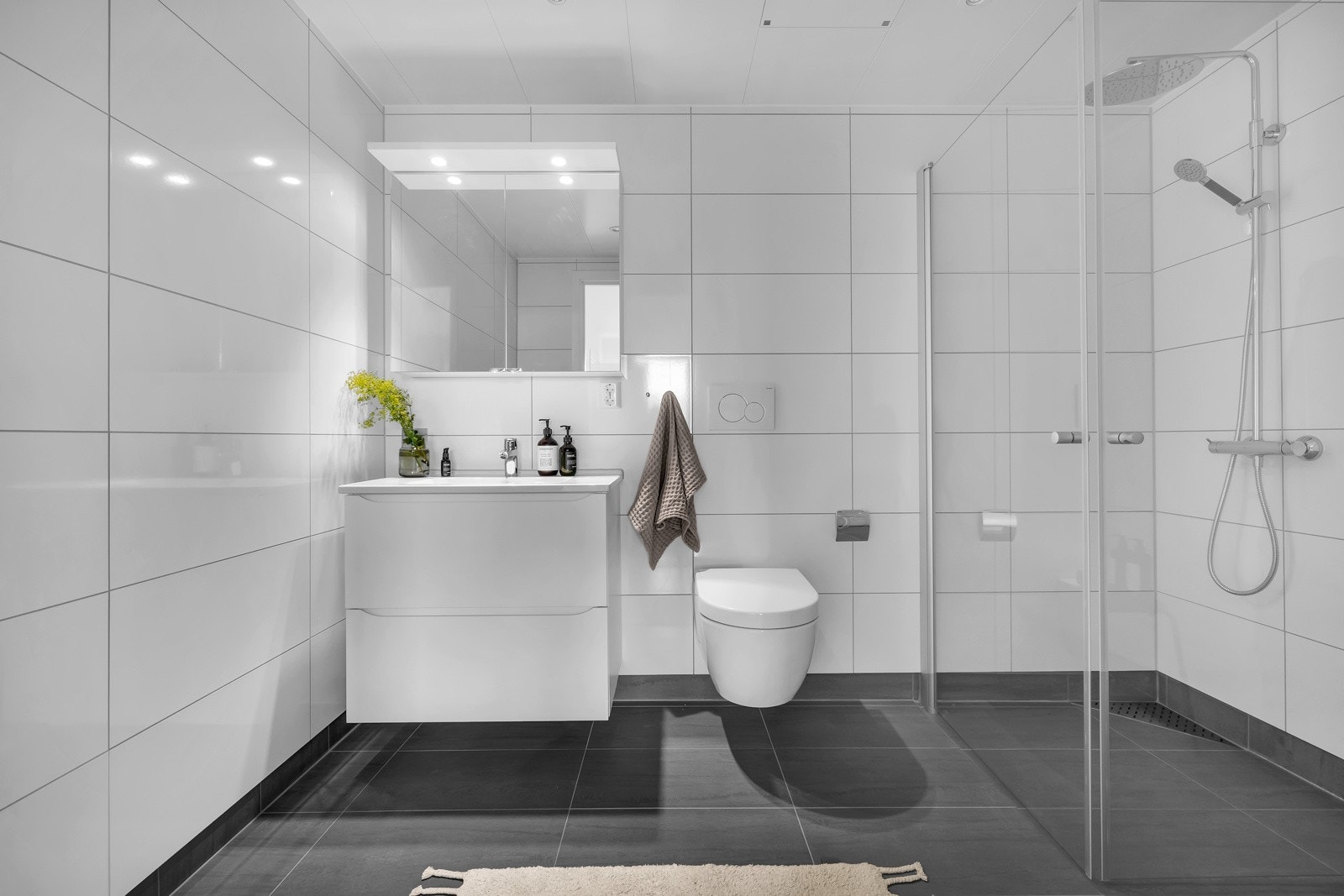 Også dette badet er pent flislagt på gulv og vegger. Vegghengt toalett og innfellbare glassvegger i dusjsonen Galleribilde