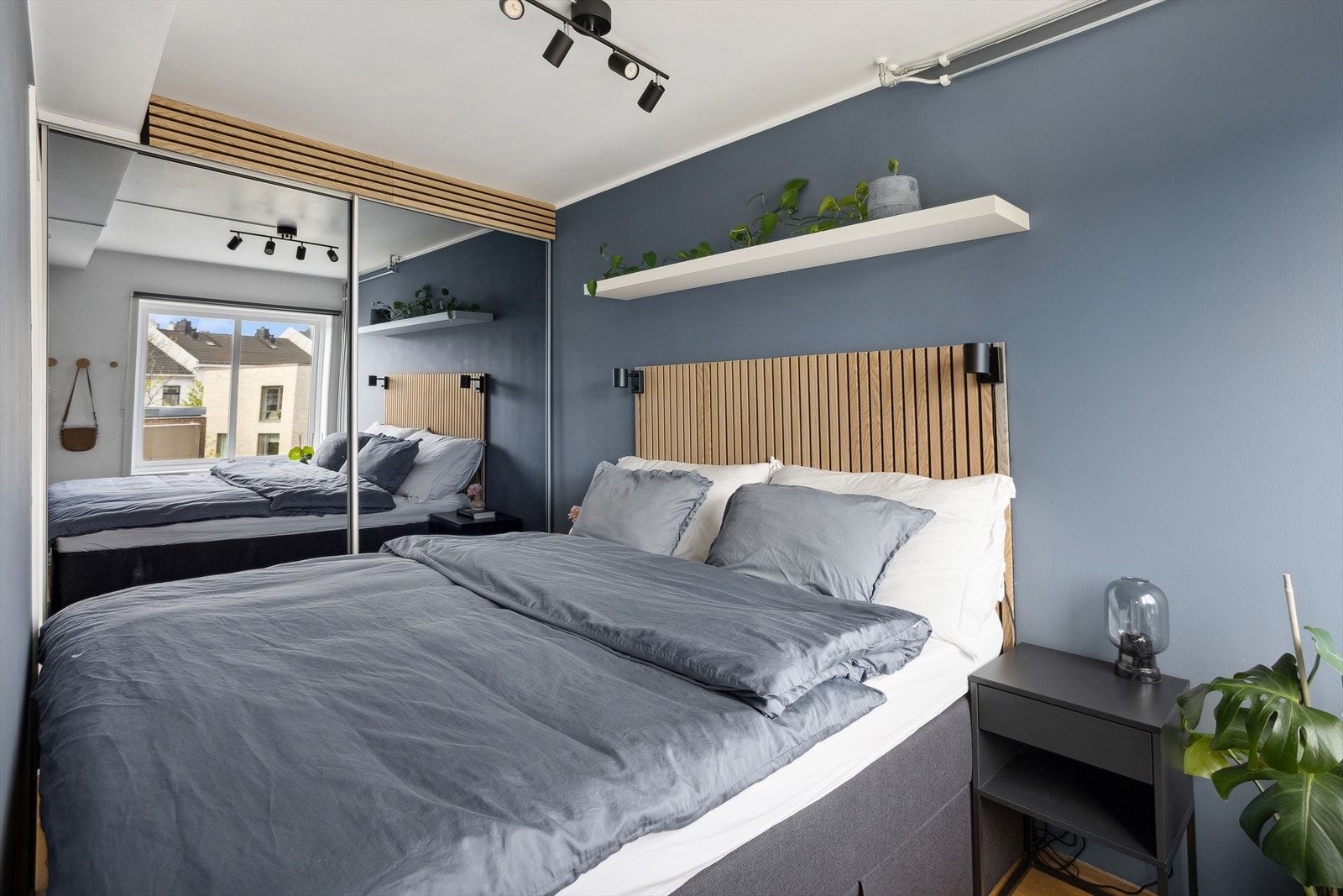 Innerst i rommet er det montert en stor skyvedørsgarderobe med speilfronter. Galleribilde