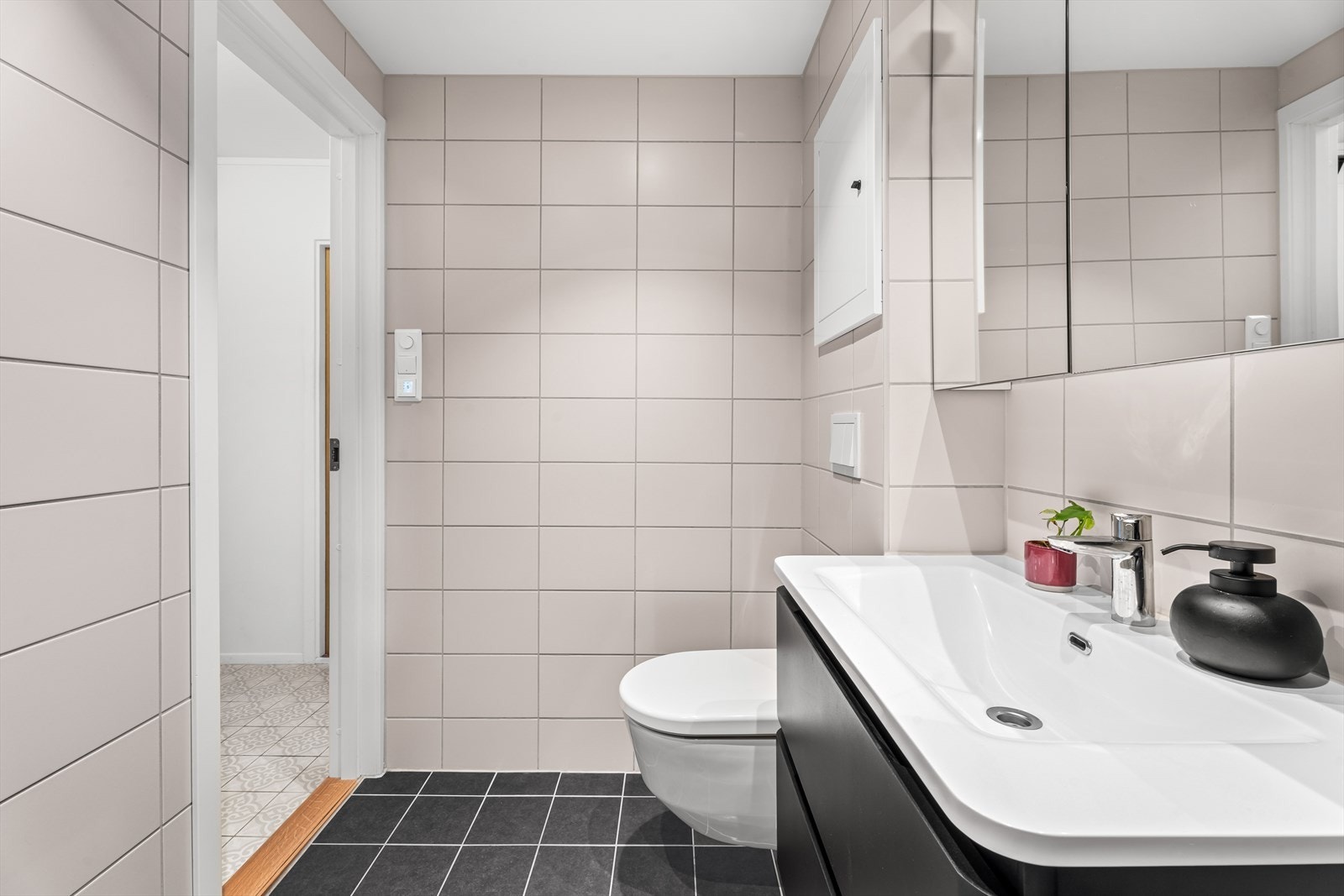 Badet har behagelig gulvvarme og opplegg for vaskemaskin. Veggfestet klosett med innebygget sisterne, og downlights i himling. Galleribilde