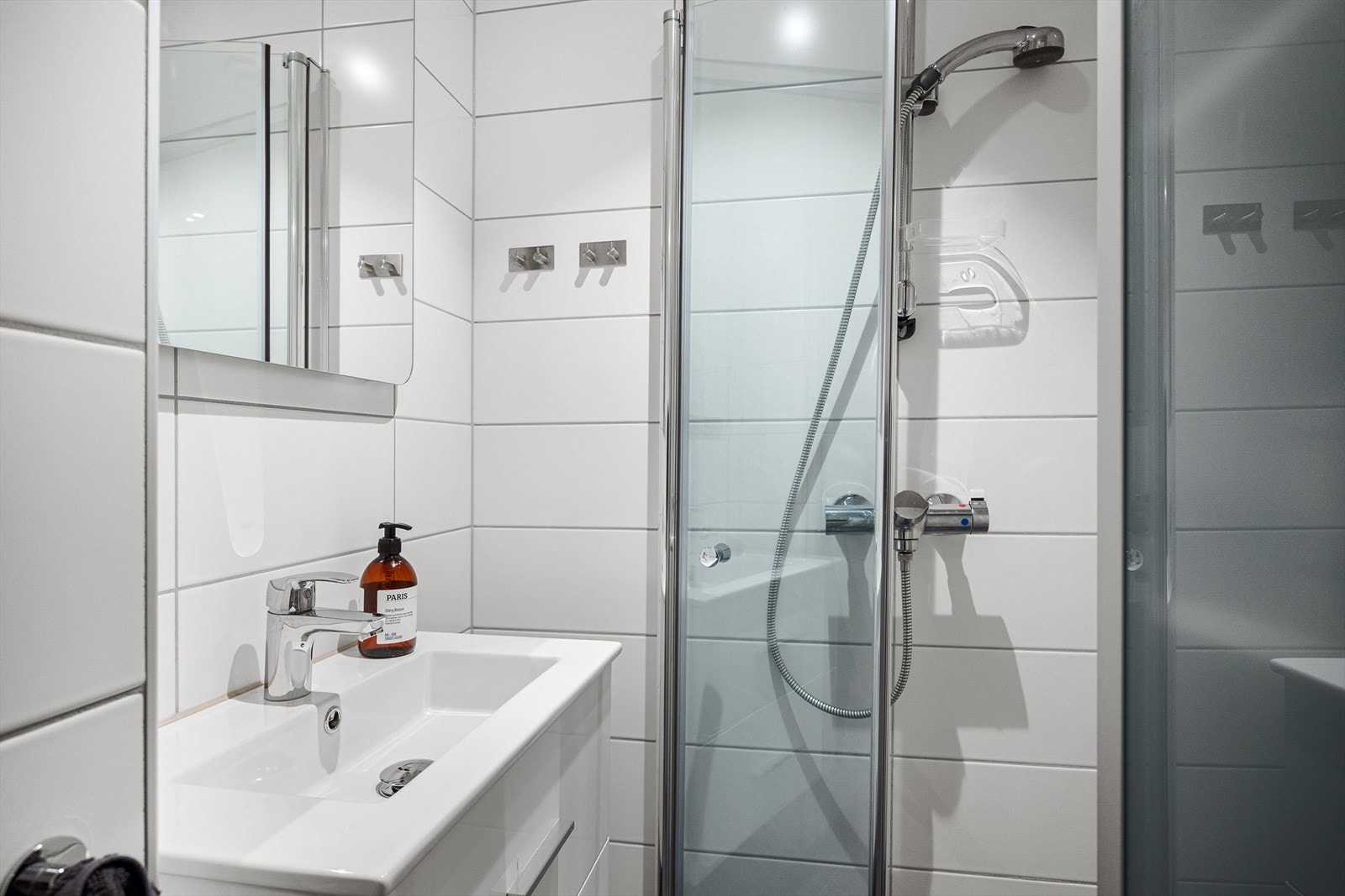 Badet består av servantskap, speil med innebygd lys, vegghengt toalett og innfellbare dusjvegger i glass. Galleribilde