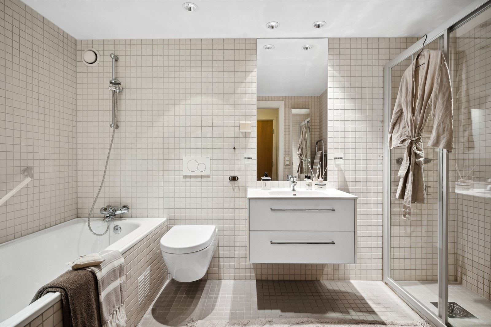 Pent og tidløst baderom med både badekar og stor dusjløsning Galleribilde