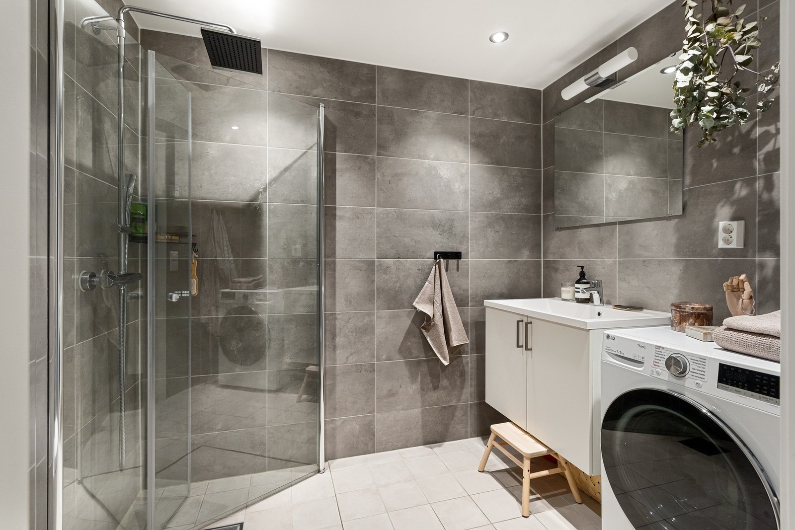 Badet er moderne innredet med lysegrå fliser på gulv og mørkegrå fliser på veggene Galleribilde