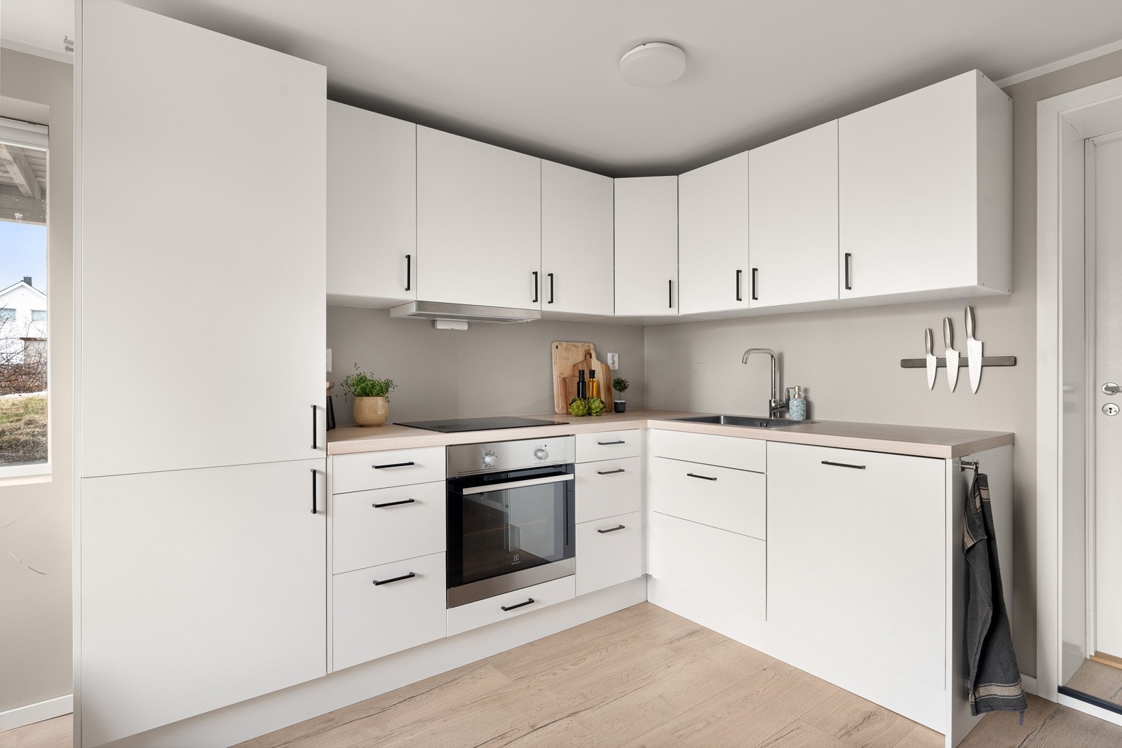 Delikat kjøkken med lyse fronter og svarte håndtak, samt integrerte hvitevarer. Galleribilde