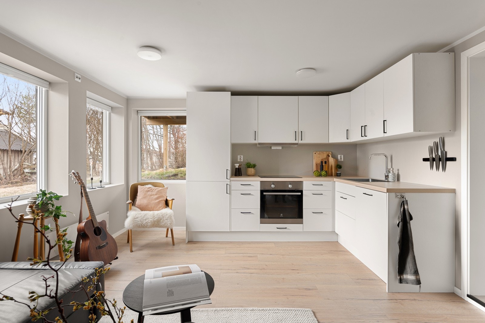 Åpen løsning mellom stue og kjøkken. Tidsriktige fargevalg på vegg og lys 1-stavs laminat på gulv. Galleribilde