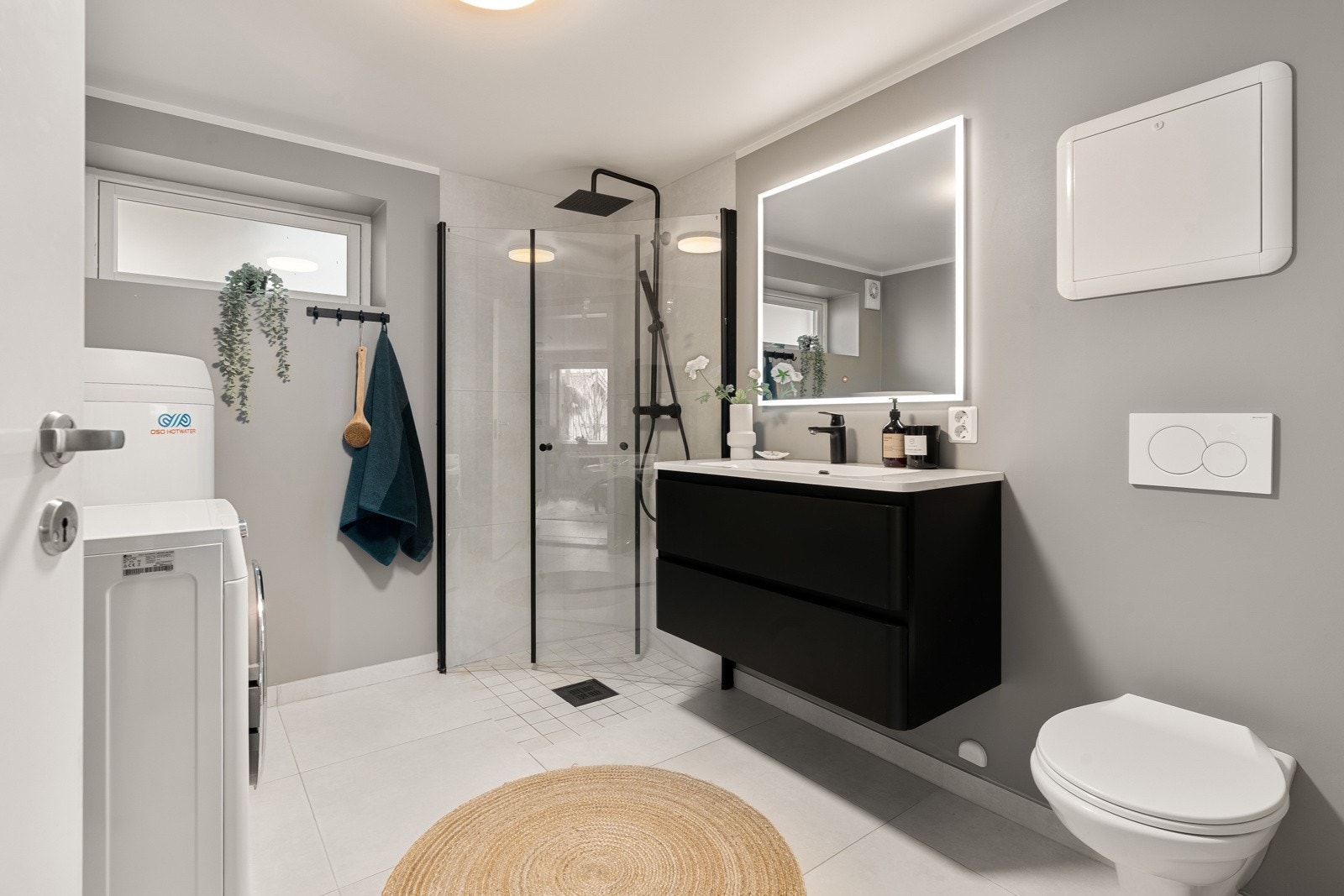 Badet framstår romslig med stort dusjhjørne, praktisk vegghengt wc og opplegg for vaskemaskin. Galleribilde