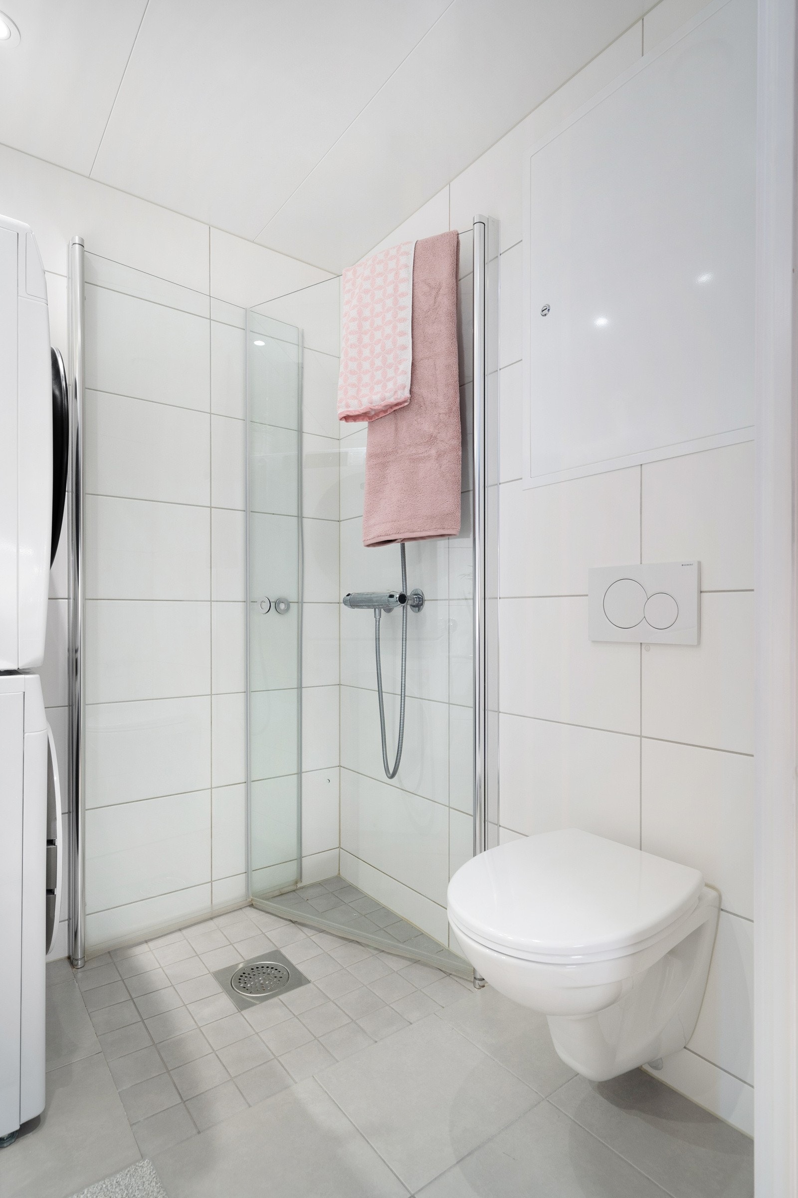 Pent flislagt baderom med moderne innredning og innfellbare dusjdører i glass. Galleribilde