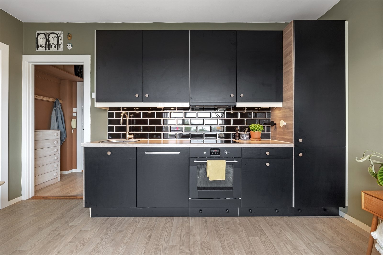 - Kjøkkeninnredning med glatte fronter. Laminat benkeplate med nedfelt vask. Fliser og belysning over benkeplaten. Kjøkkenskap er laminert - Galleribilde