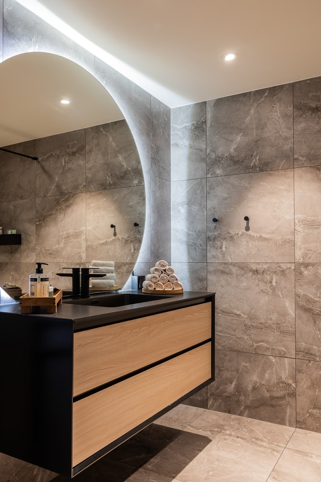 Alle baderomsmøbler er fra Nygaard bad. Garnityr fra tapwell. Spesiallaget rist til begge sluk i dusj i matt sort. Belysning bak speil kan styres av Plejd-system app. Gulvvarme. Galleribilde