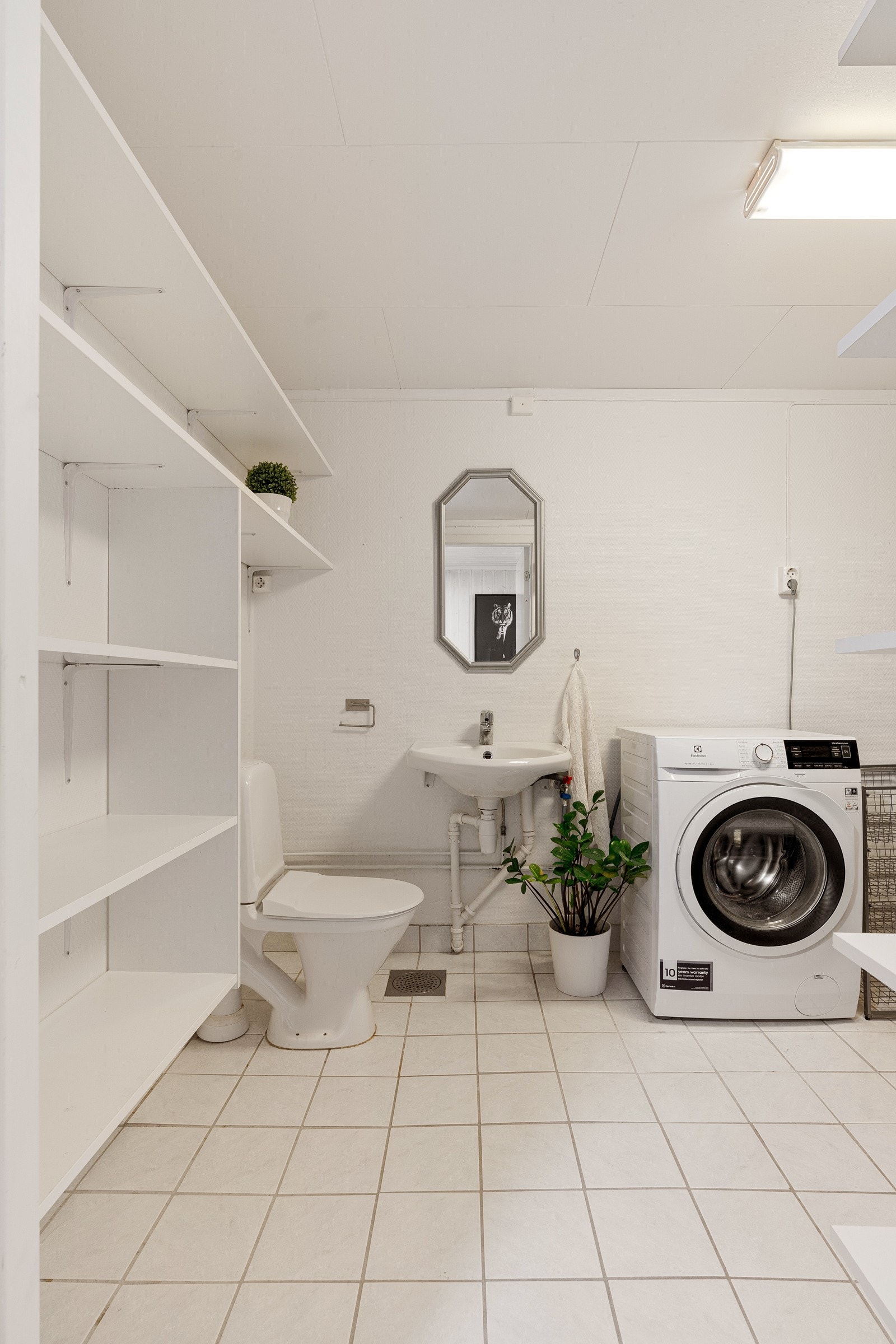 Flislagt vaskerom i kjeller med ekstra toalett og praktiske hylleløsning. Galleribilde