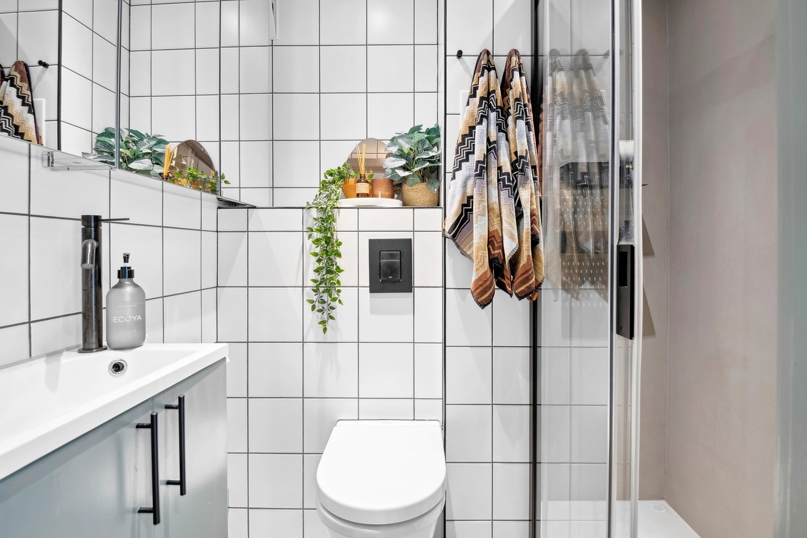 Veggmontert wc, dusjplass med vegger og servant med ettgreps blandebatteri i innredning Galleribilde