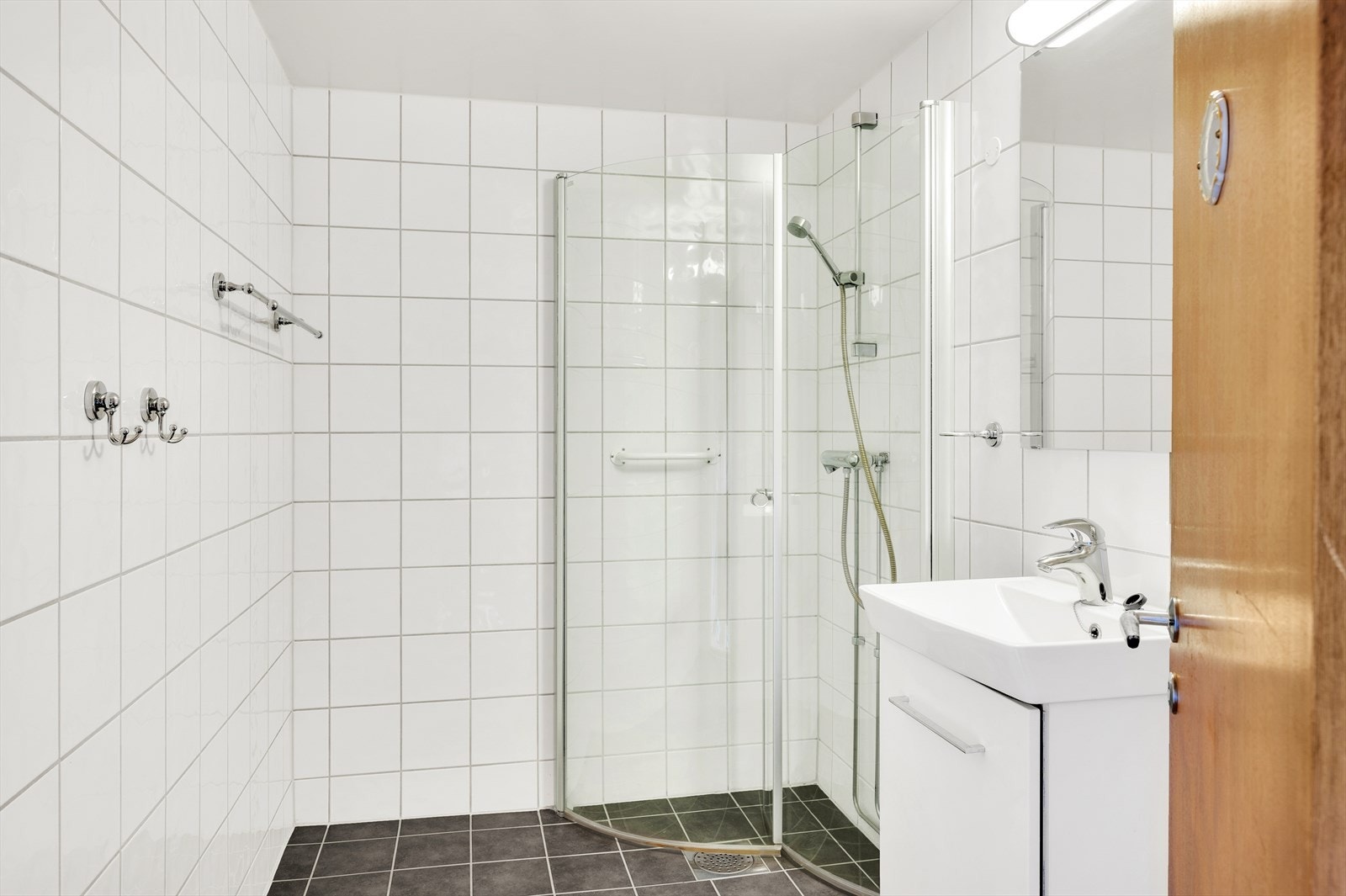 Flislagt bad med varmekabler. Badet har dusj på gulv med dører i herdet glass. Galleribilde