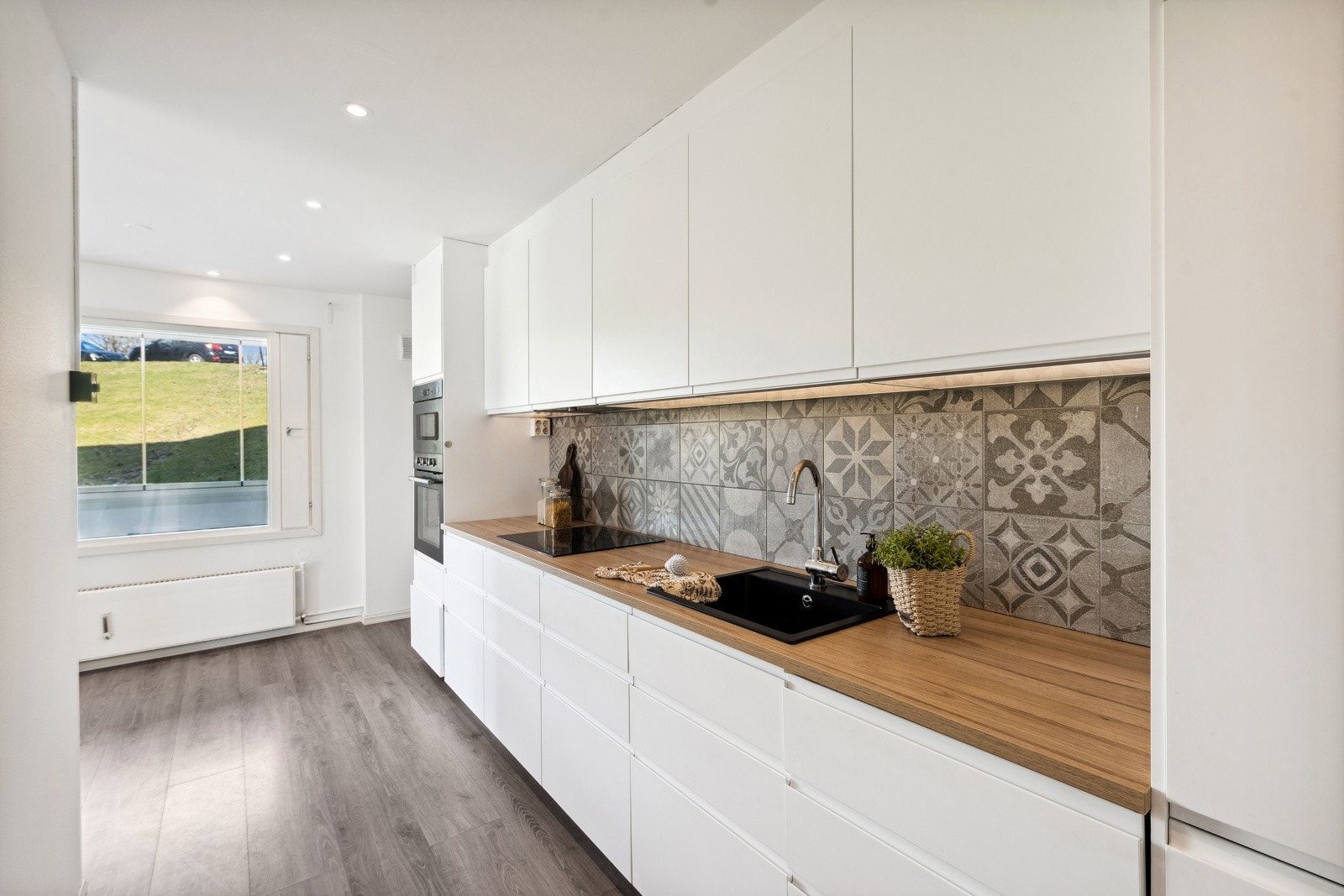 Pent Ikea kjøkken fra 2019 med laminat benkeplate og fliser på vegg over kjøkkenbenken. Galleribilde
