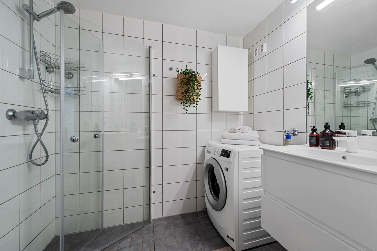 Innredning med vegghengt klosett, servantinnredning, servant med ettgreps blandebatteri, dusjdører, dusjarmatur, opplegg og plass til vaskemaskin. Galleribilde