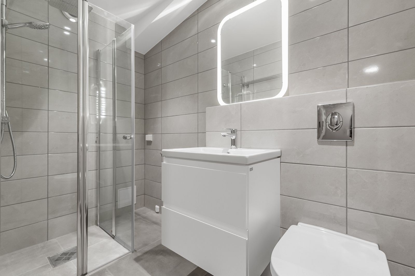 Lekkert flislagt bad med varmekabler i gulv og opplegg til vaskemaskin Galleribilde