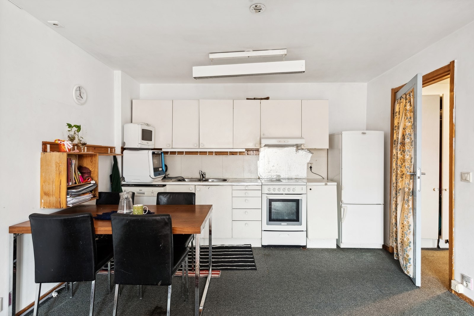 KJØKKEN | Kjøkkenet ligger i åpen løsning mot stuen. Eldre kjøkkeninnredning fra byggeår med malte glatte fronter, laminat benkeplate og dobbel oppvaskkum i stål. Frittstående hvitevarer som komfyr og opplegg for oppvaskmaskin. Det er avtrekksvifte med ut Galleribilde