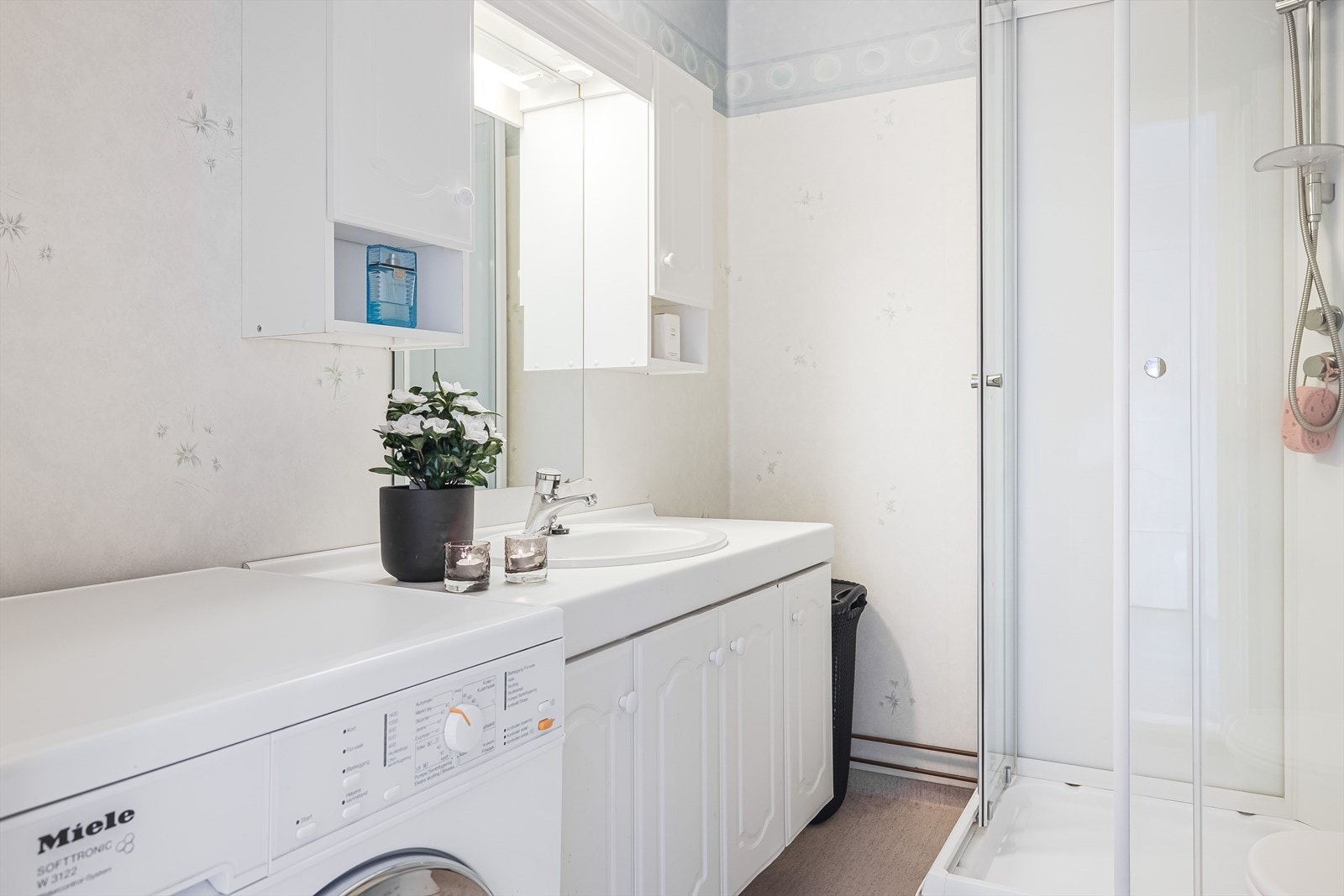 Badet er utstyrt med baderomsinnredning med benkeplate og nedfelt servant med ett-greps blandebatteri. I overkant er det veggskap, speil, lys og elektrisk uttak. Galleribilde