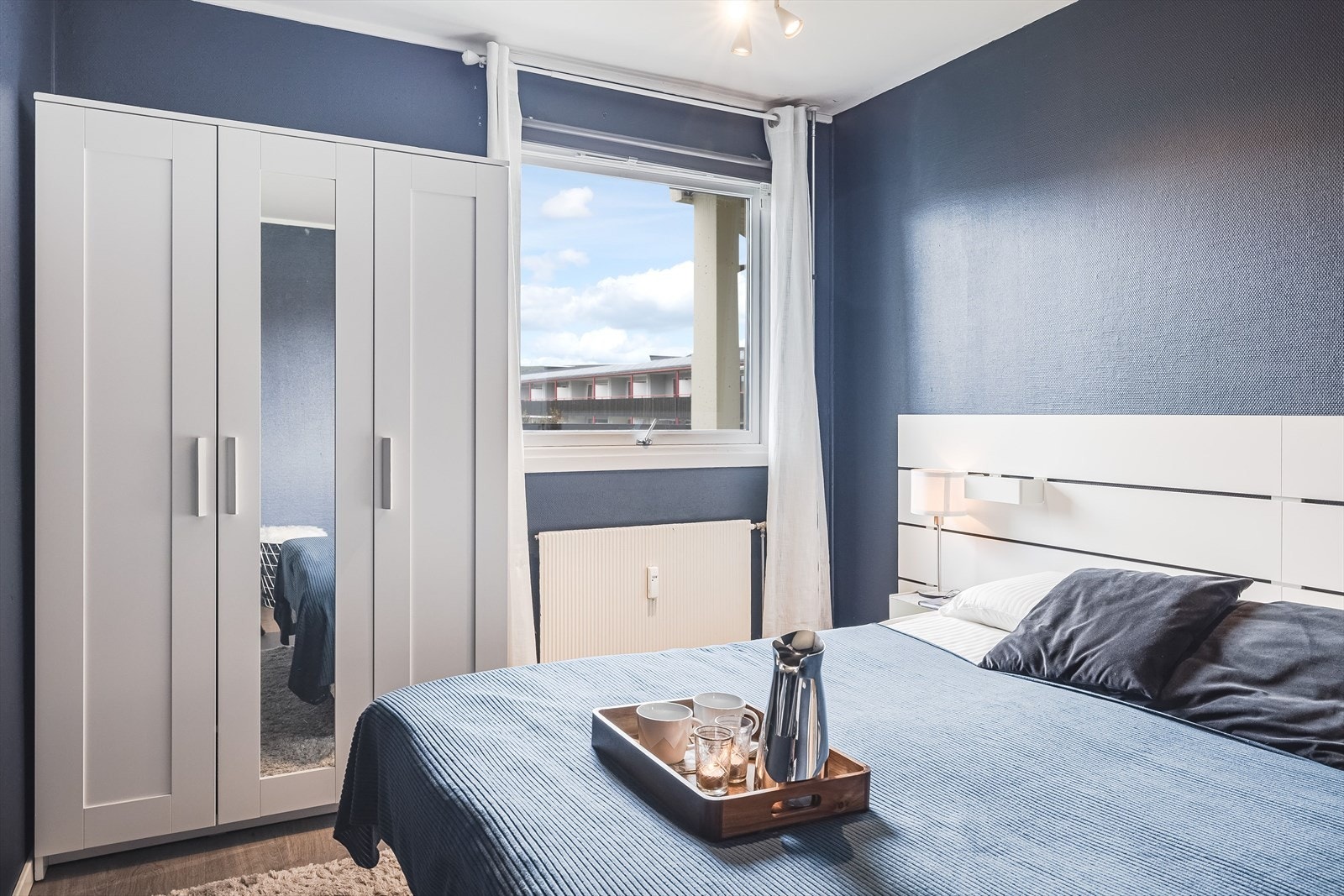Leilighetens soverom har samme gulv som stua og veggene er mal i en mellomblå farge. Galleribilde