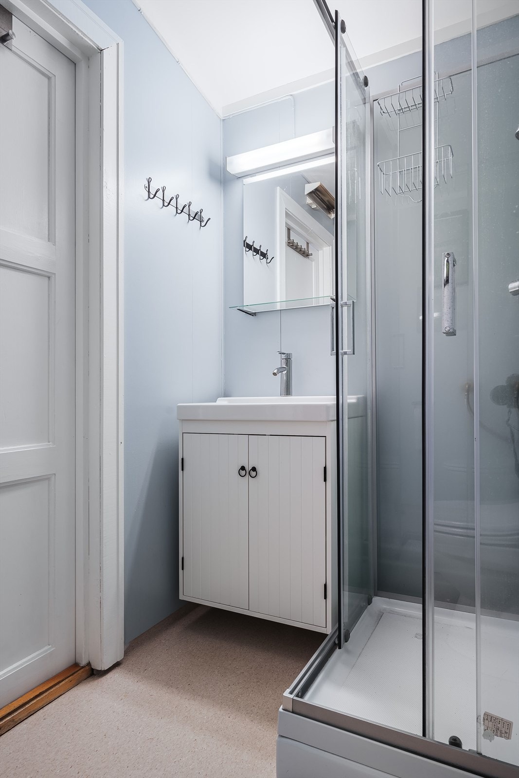 Baderommet er utstyrt med servantskap, speil med belysning over, dusjkabinett og gulvstående toalett. Galleribilde