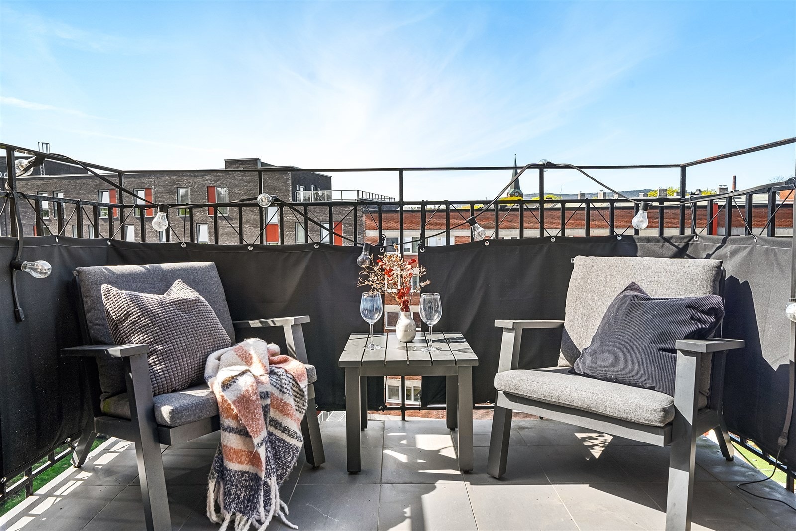 Nordvestvendt balkong på 4 m² med flislagt dekke, brystning i stål, skjermduk og god plass til utemøbler. Galleribilde