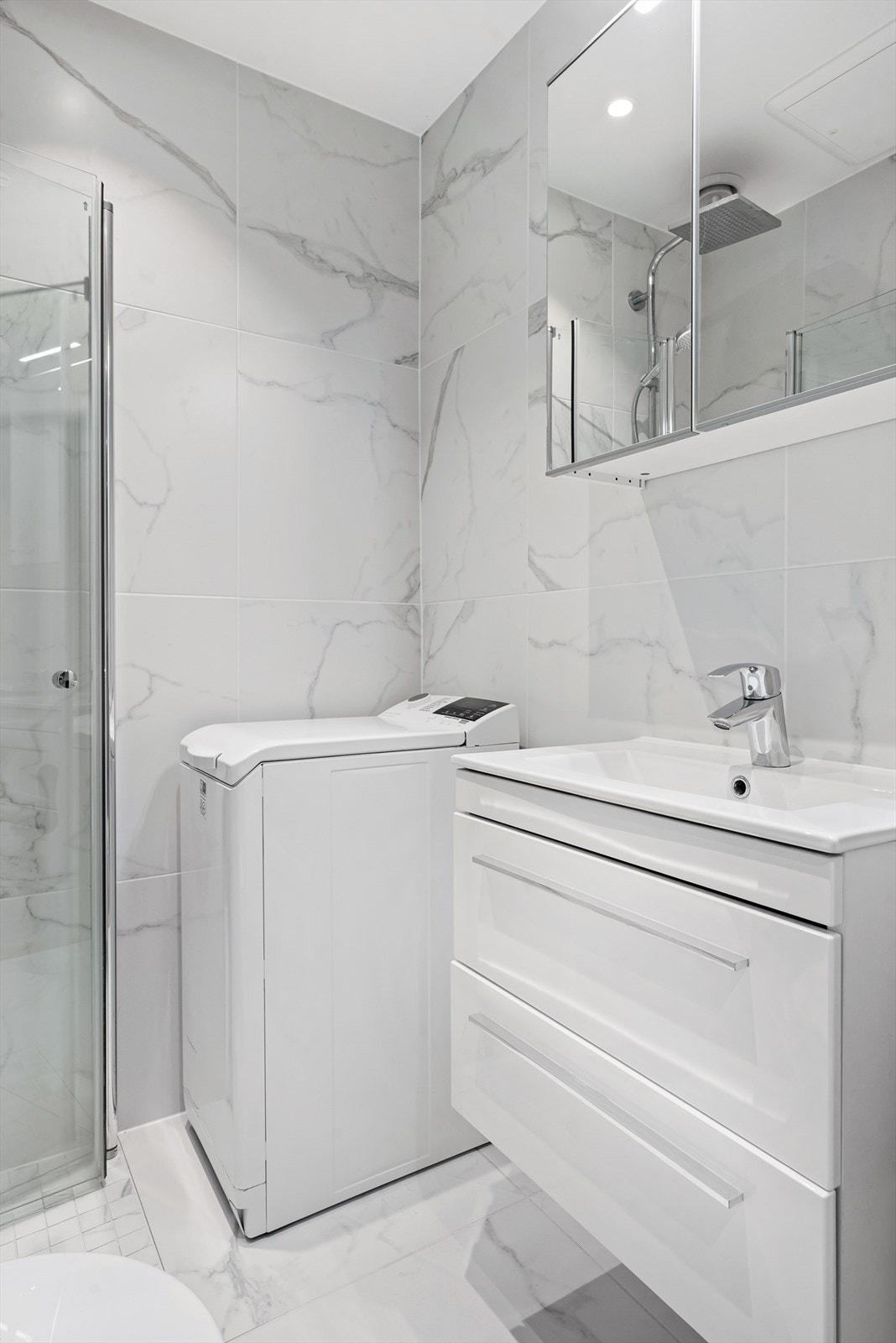 Badet har også speilskap, servantinnredning med skuffer og opplegg for vaskemaskin. Galleribilde