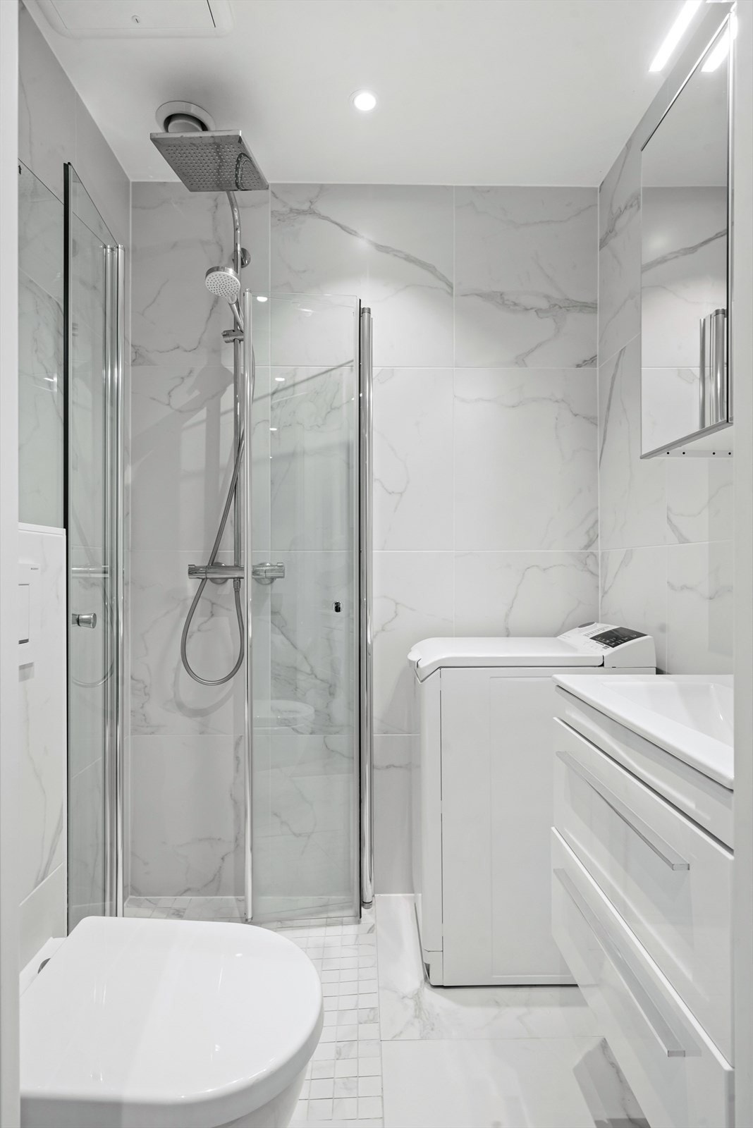 Delikat flislagt bad fra 2019 med downlights og varmekabler. Vegghengt wc og dusjhjørne med foldedører i glass, regndusj og hånddusj. Galleribilde