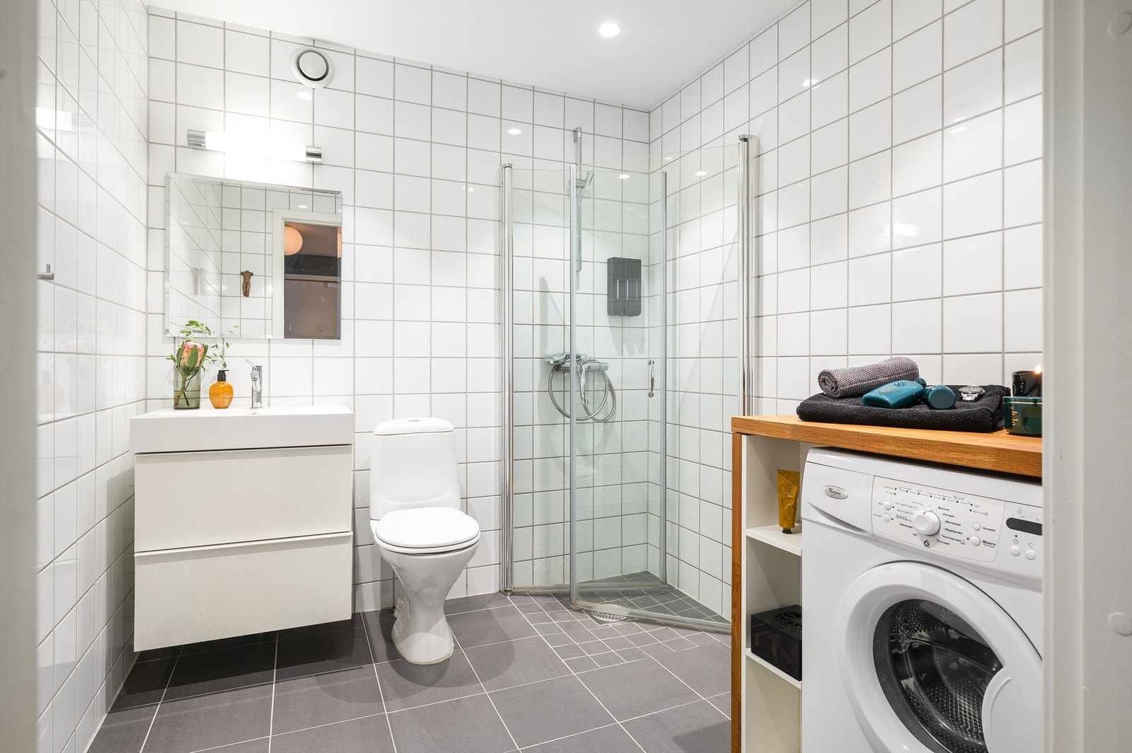 Videre har badet dusjhjørne med innfellbare dører i glass og klosett. Det er opplegg for vaskemaskin. Galleribilde