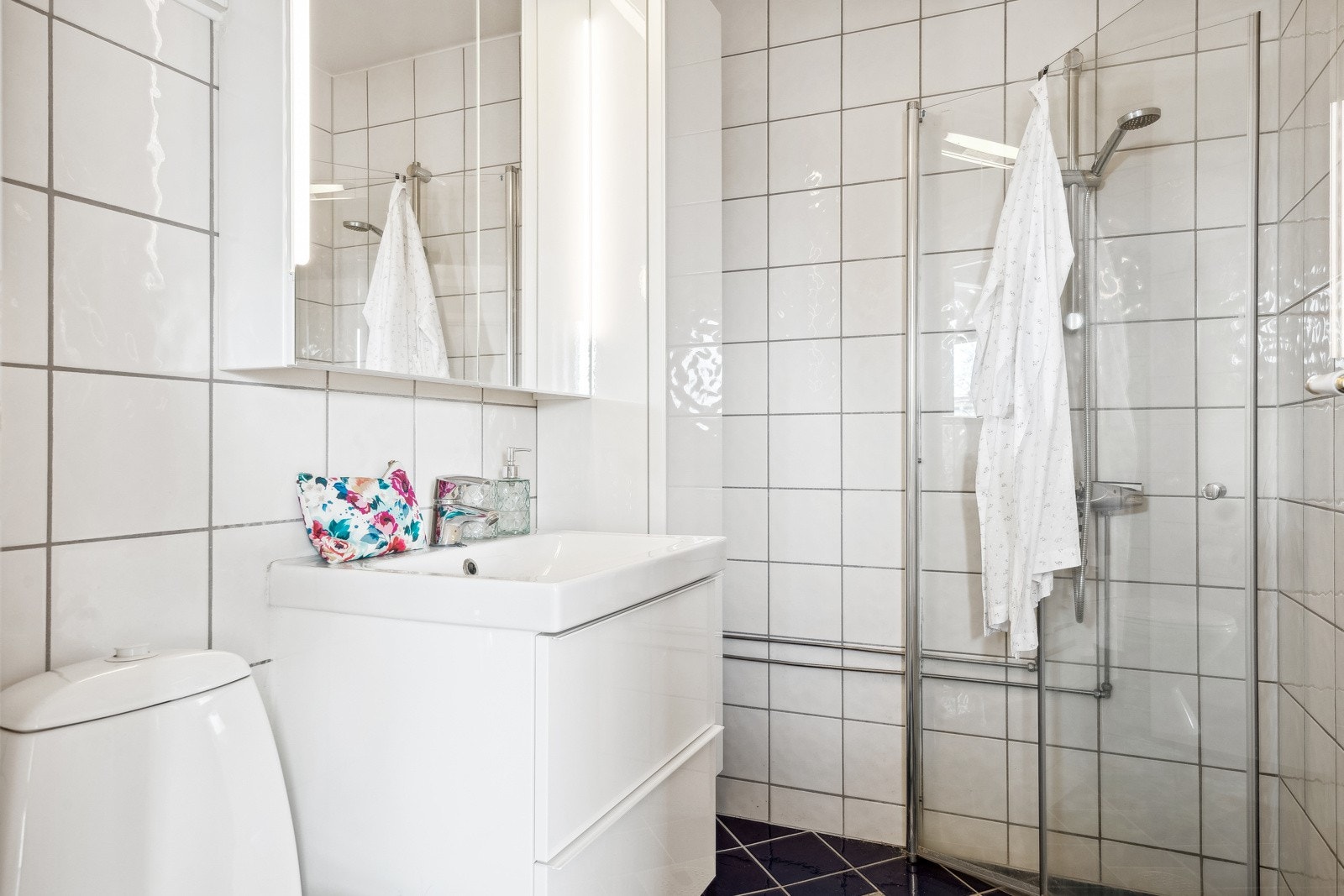Badet måler 3 kvm og er utstyrt med toalett, dusjnisje, nedfelt servant og en pen baderomsinnredning med skuffeseksjoner. Det er god plass til oppbevaring av toalettartikler i vegg- og speilskap. Galleribilde