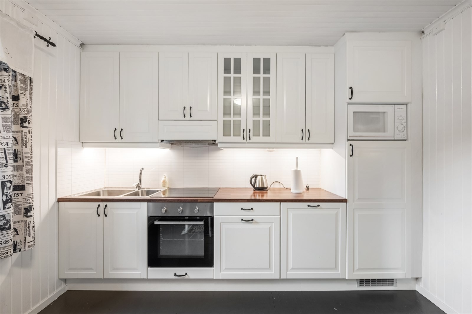 Kjøkkenet har godt med over- og underskap med profilerte fronter fra 2008. Benkeplate av laminat, integrerte hvitevarer som komfyr, platetopp og kjøleskap er å finne. Galleribilde