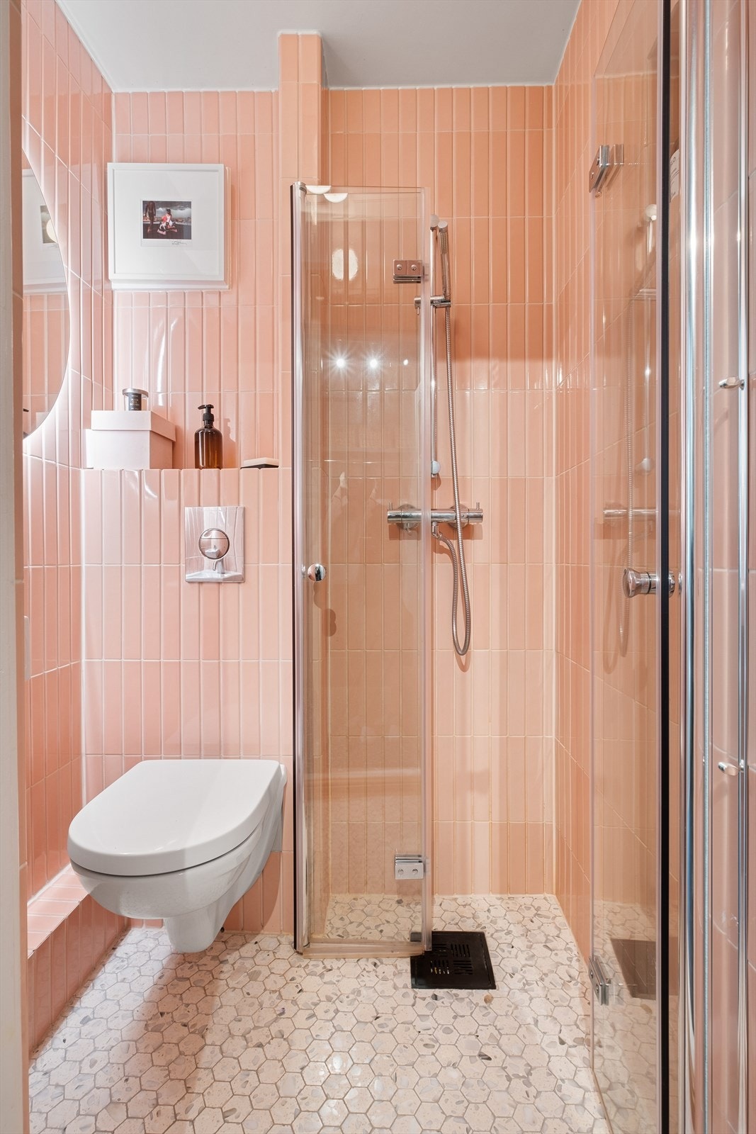 Flislagt baderom fra 2021 med adkomst fra entré. Badet har varme i gulvet. Innredet med vegghengt klosett, servant og dusjhjørne med svingbare glassdører. Naturlig avtrekk. Galleribilde