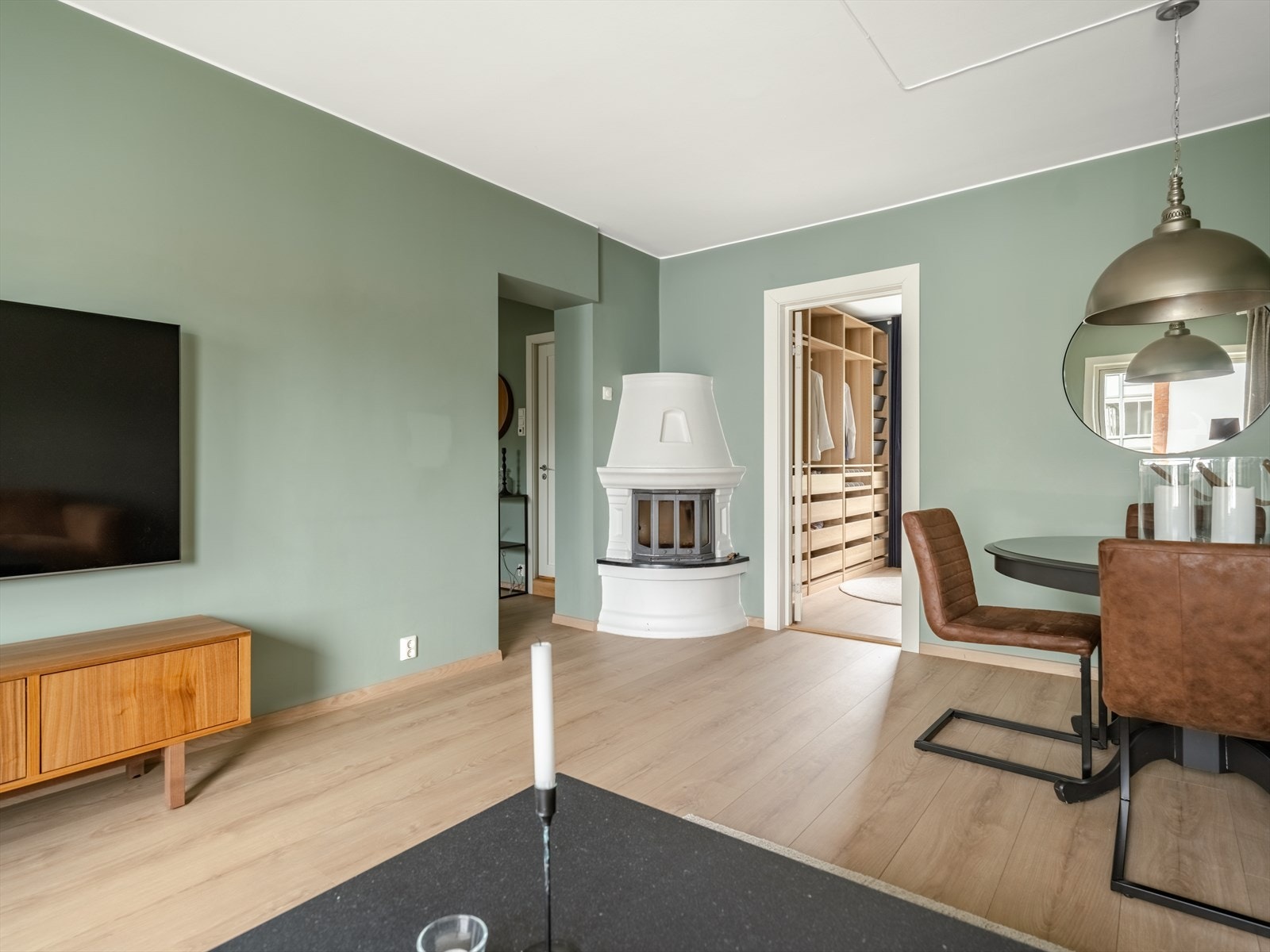 Med lyse gulv og vegger malt i en moderne nyanse, har leiligheten en høy sjarmfaktor. Det er også en hyggelig vedovn i hjørnet som sikrer varme vinterkvelder. Galleribilde