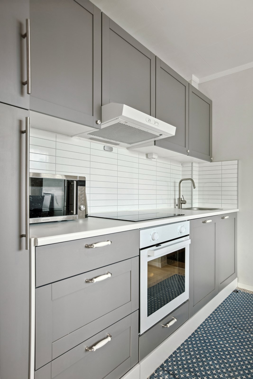 Pen innredning med integrerte hvitevarer som komfyr, platetopp og oppvaskmaskin. Avsatt plass til frittstående kjøleskap. Galleribilde