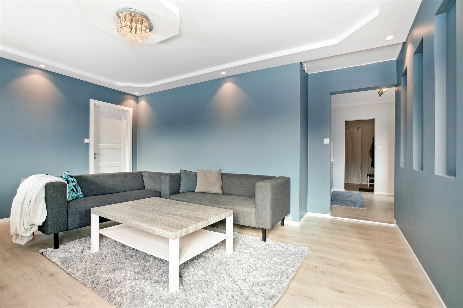 Stuen har moderne farger på vegg og pent gulv samt downlights i tak. Galleribilde