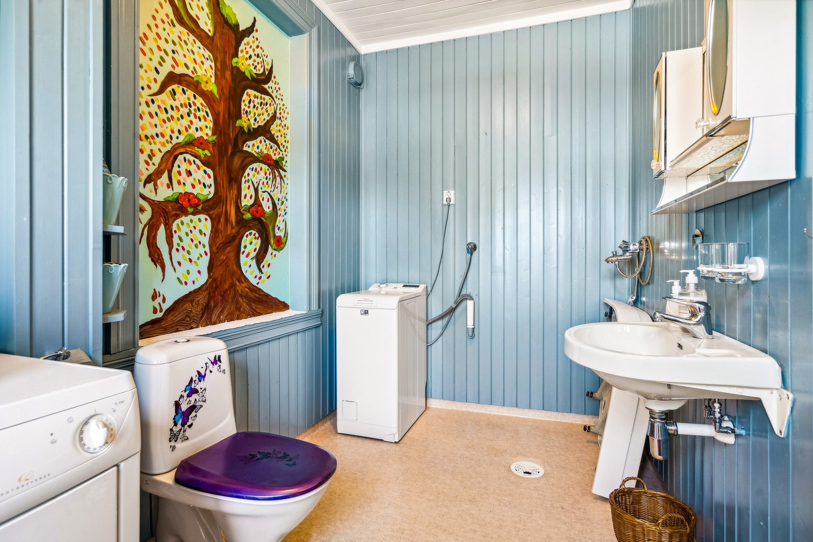 Bad/vaskerom fremstår med belegg på gulv, malt panel på vegger og i tak. Innredning med servant, blandebatteri til dusjhjørne, opplegg til vaskemaskin og gulvmontert toalett Galleribilde