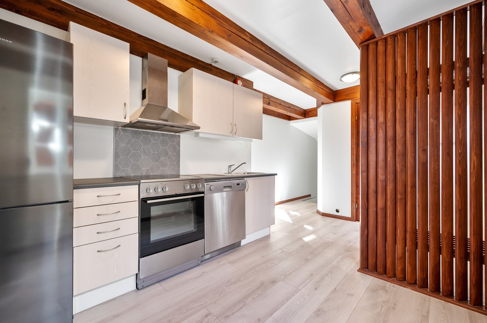 Kjøkken har innredning med lyse trefarget fronter, laminat benkeplate, og hvitevarer i stål. Galleribilde