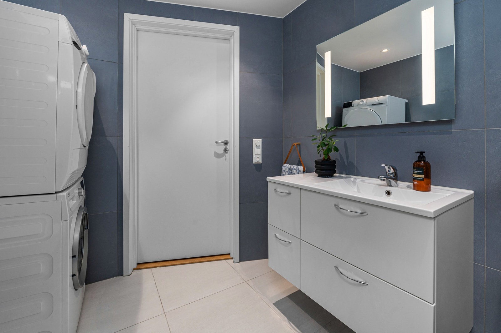 Badet er utstyrt med opplegg til vaskemaskin, innfellbare dusjvegger, vegghengt toalett og servantskap med skapplass. Galleribilde