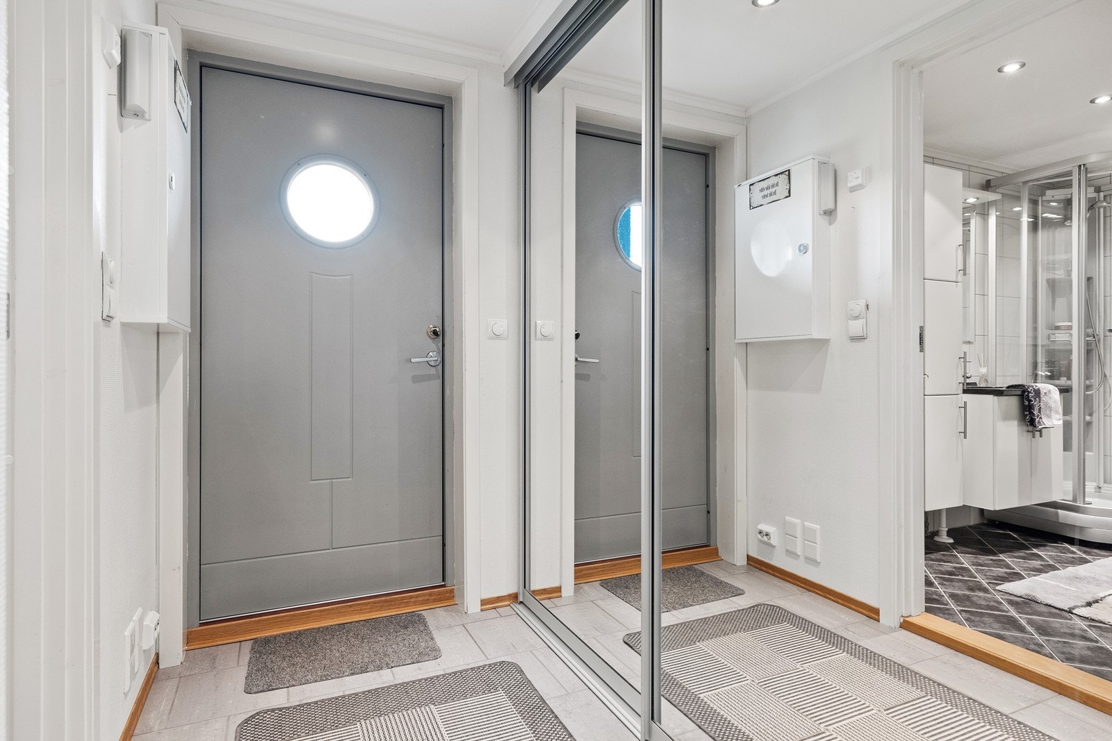 En lys og smal gang med innebygd skyvedørsgarderobe langs den ene veggen med god plass til oppbevaring. Galleribilde