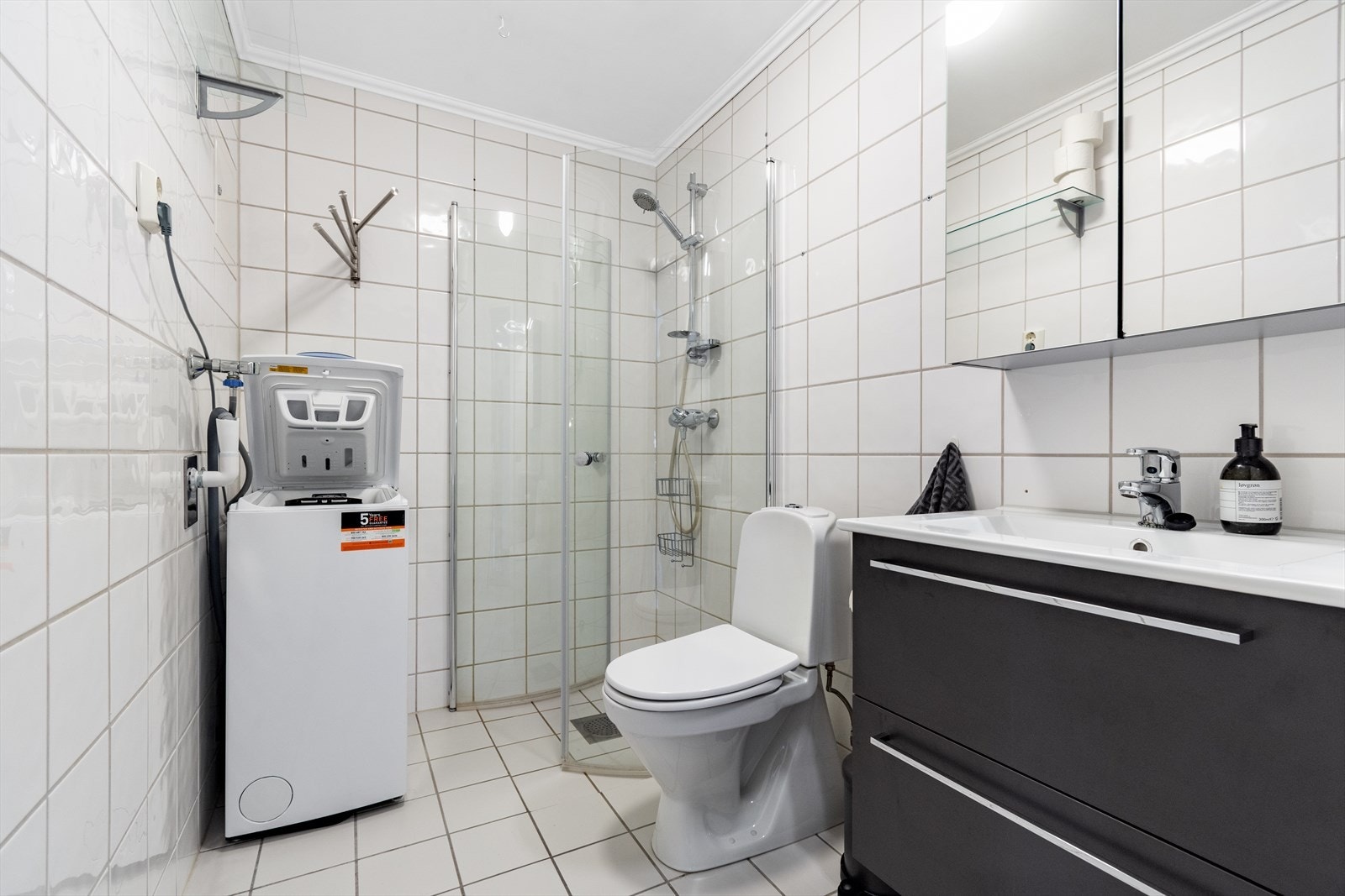 Lyst og flislagt bad på 3,5m² med gulvvarme, ferdig opplegg for vaskemaskin og moderne baderomsinnredning. Galleribilde