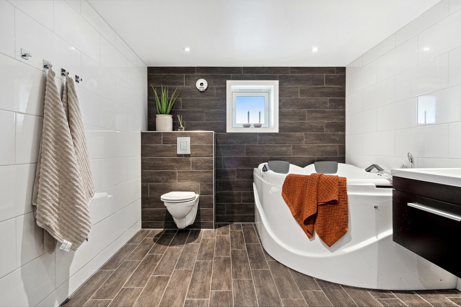 Moderne baderom utstyrt med vegghengt toalett, boblebad og servantinnredning. Galleribilde