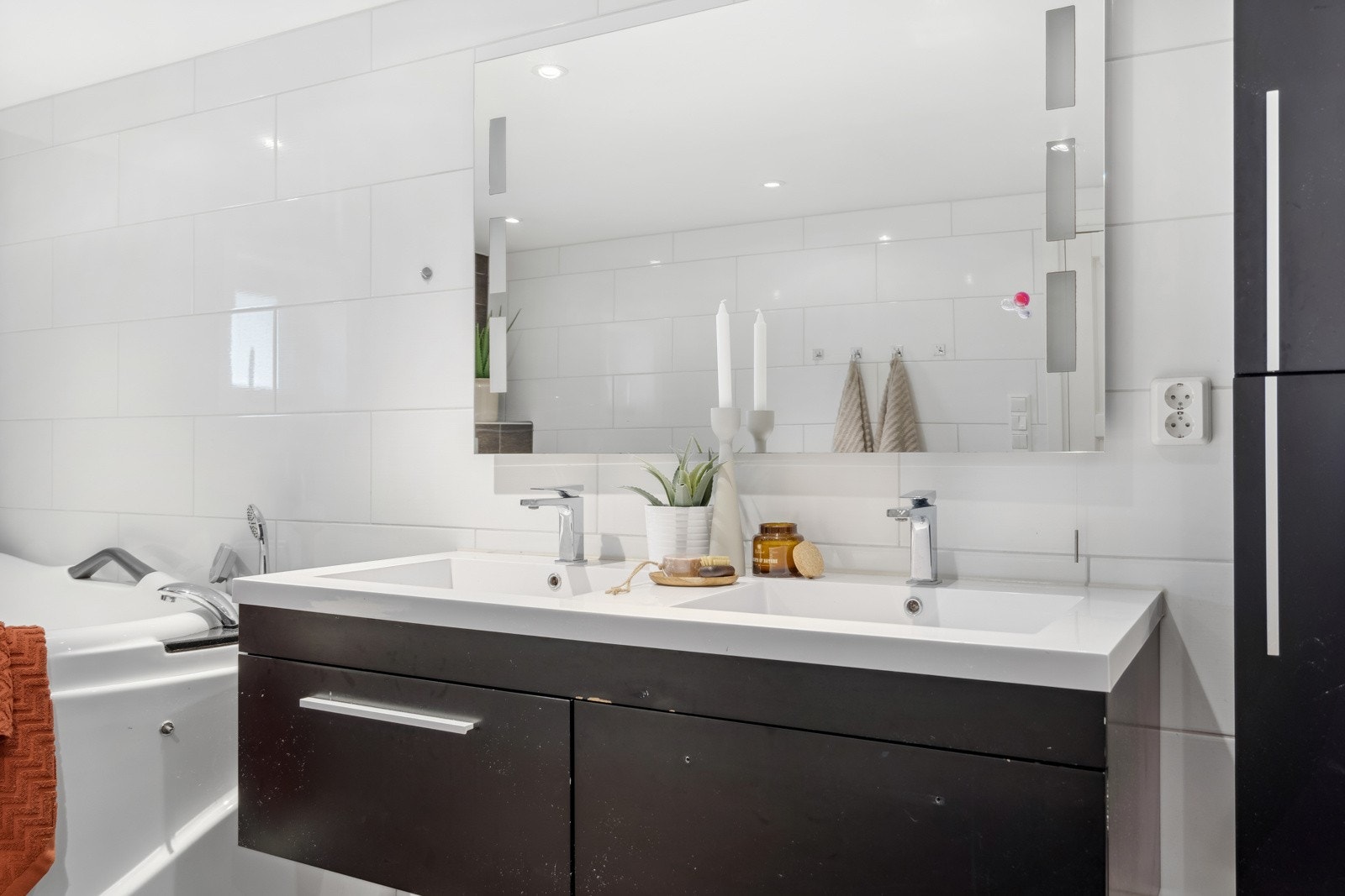 Badet har et stort speil med innebygde lys. Galleribilde