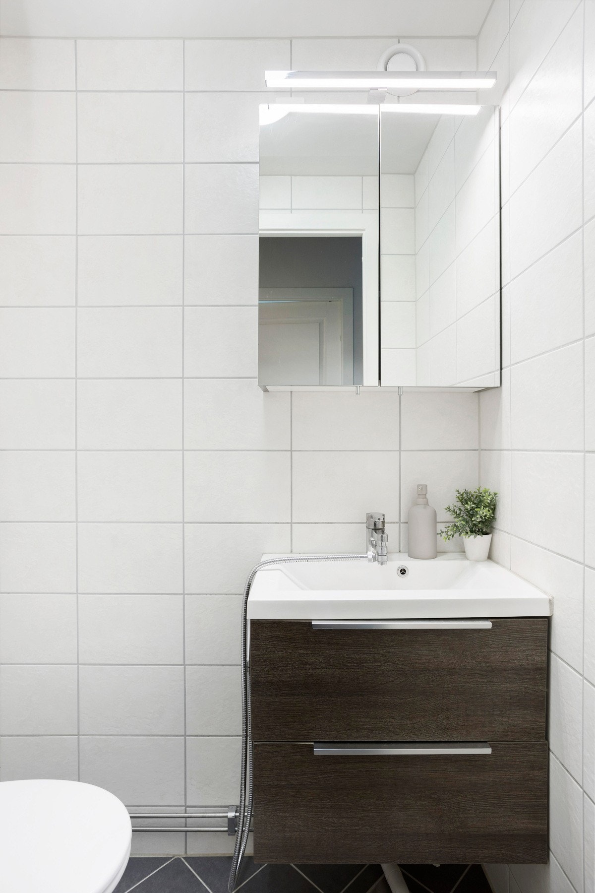 Separat toalettrom i samme stil som badet fra 2019. Vegghengt toalett, servant på underskuffer og speilskap. Galleribilde