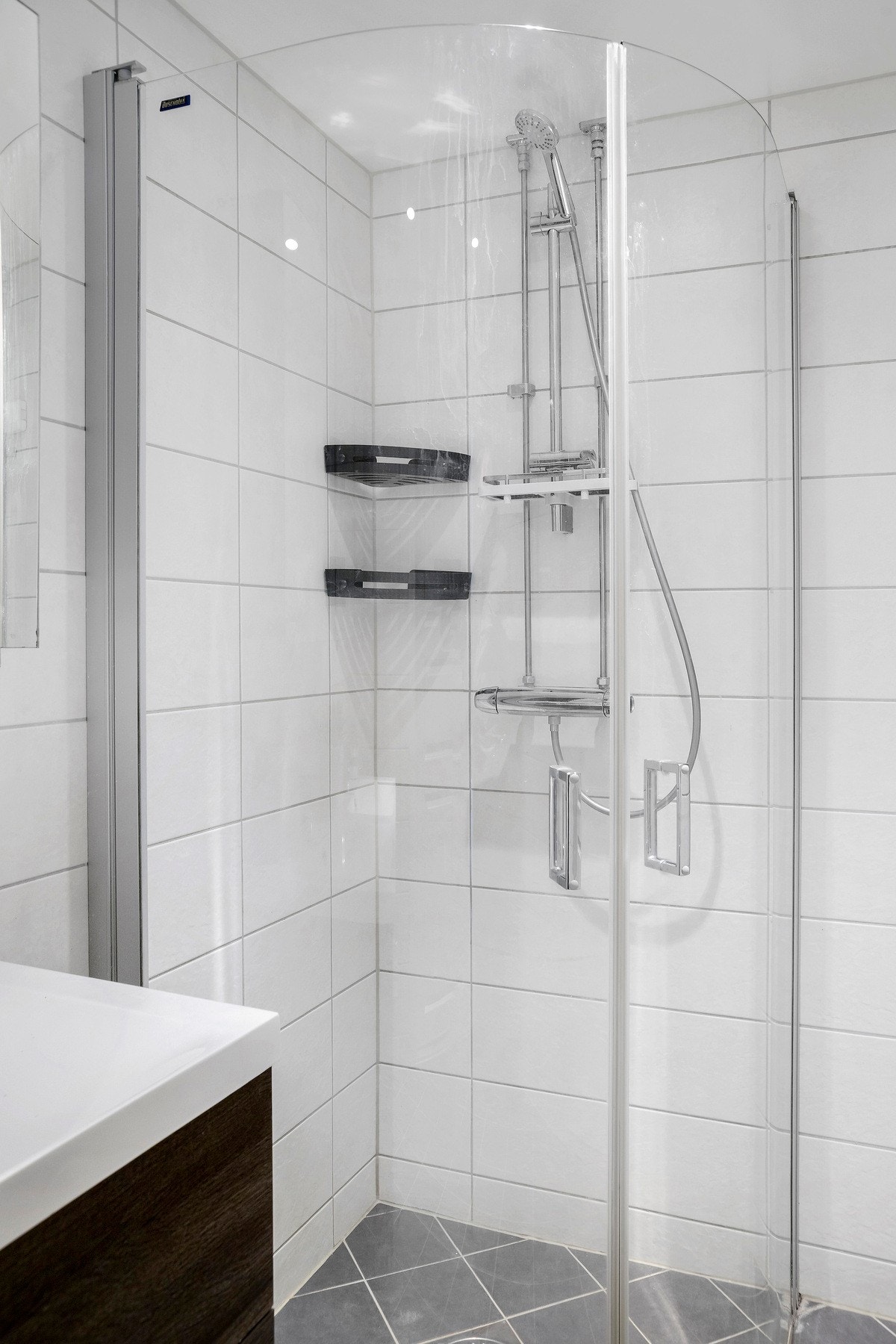 Videre er det dusjhjørne med innfellbare glassdører som frigjør plass på gulvet. Badet har opplegg for vaskemaskin. Galleribilde