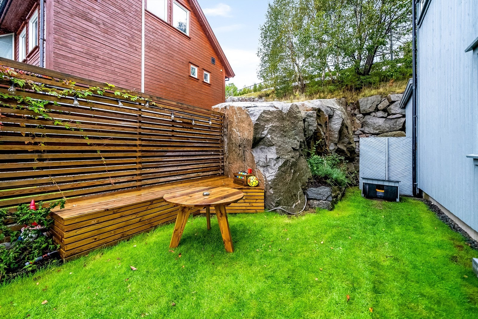 Koselig og usjenert uteplass med gjerde og plassbygd sittebenk. Galleribilde