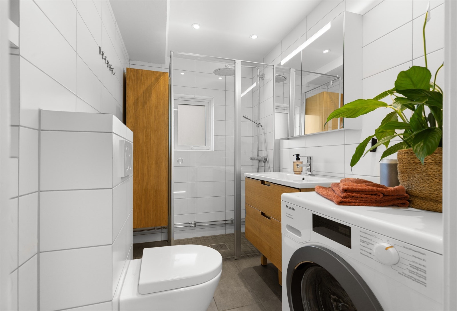 Delikat baderom fra 2017 innredet med vegghengt servantskap, speil med belysning, vegghengt høyskap, og vegghengt toalett. Nedsenket himling med innfelt downlights. Galleribilde