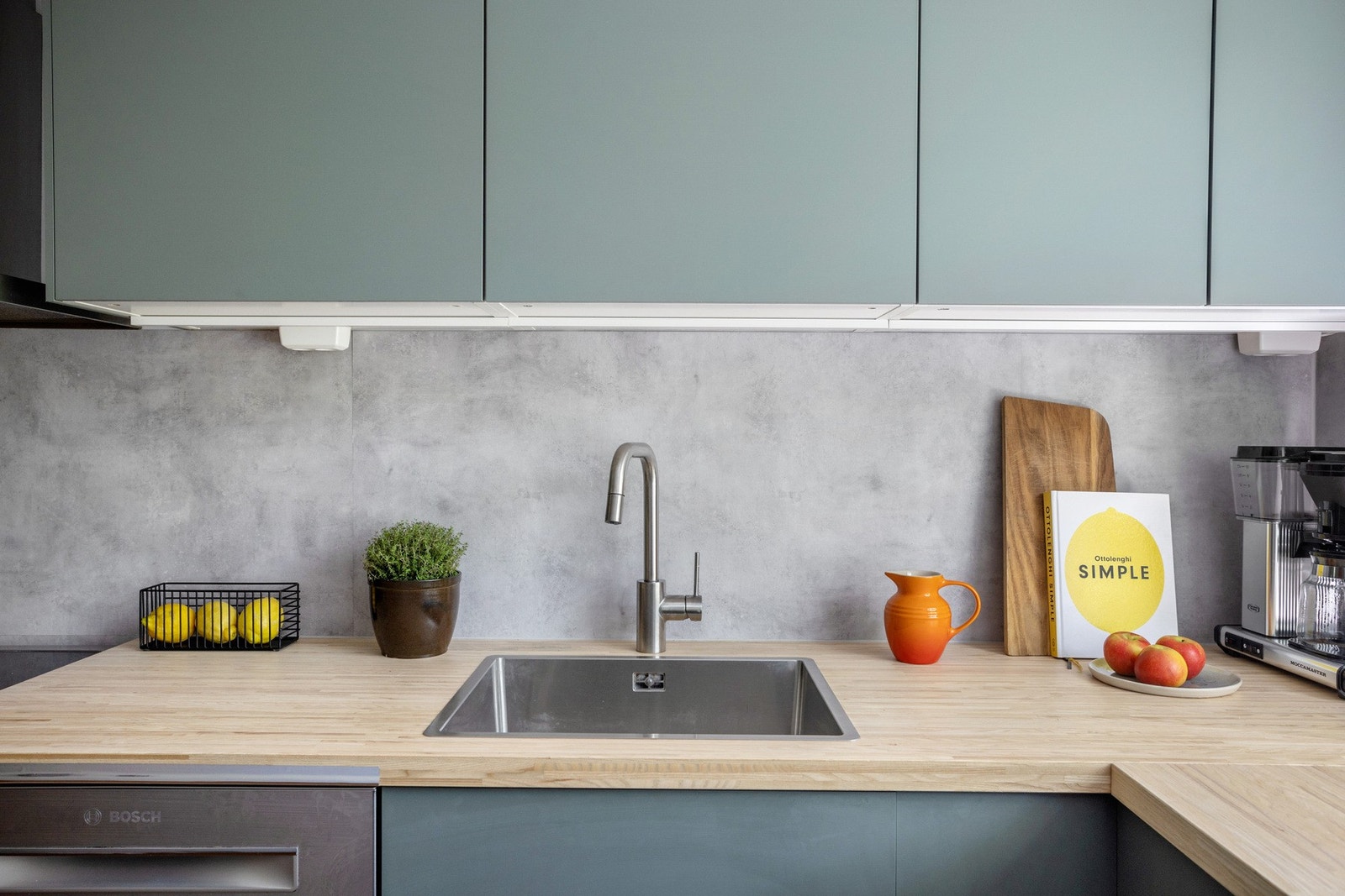 Oppvaskkum i rustfritt stål med ett-greps armatur, benkeskapsbelysning og stikkkontaker under overskap. Galleribilde