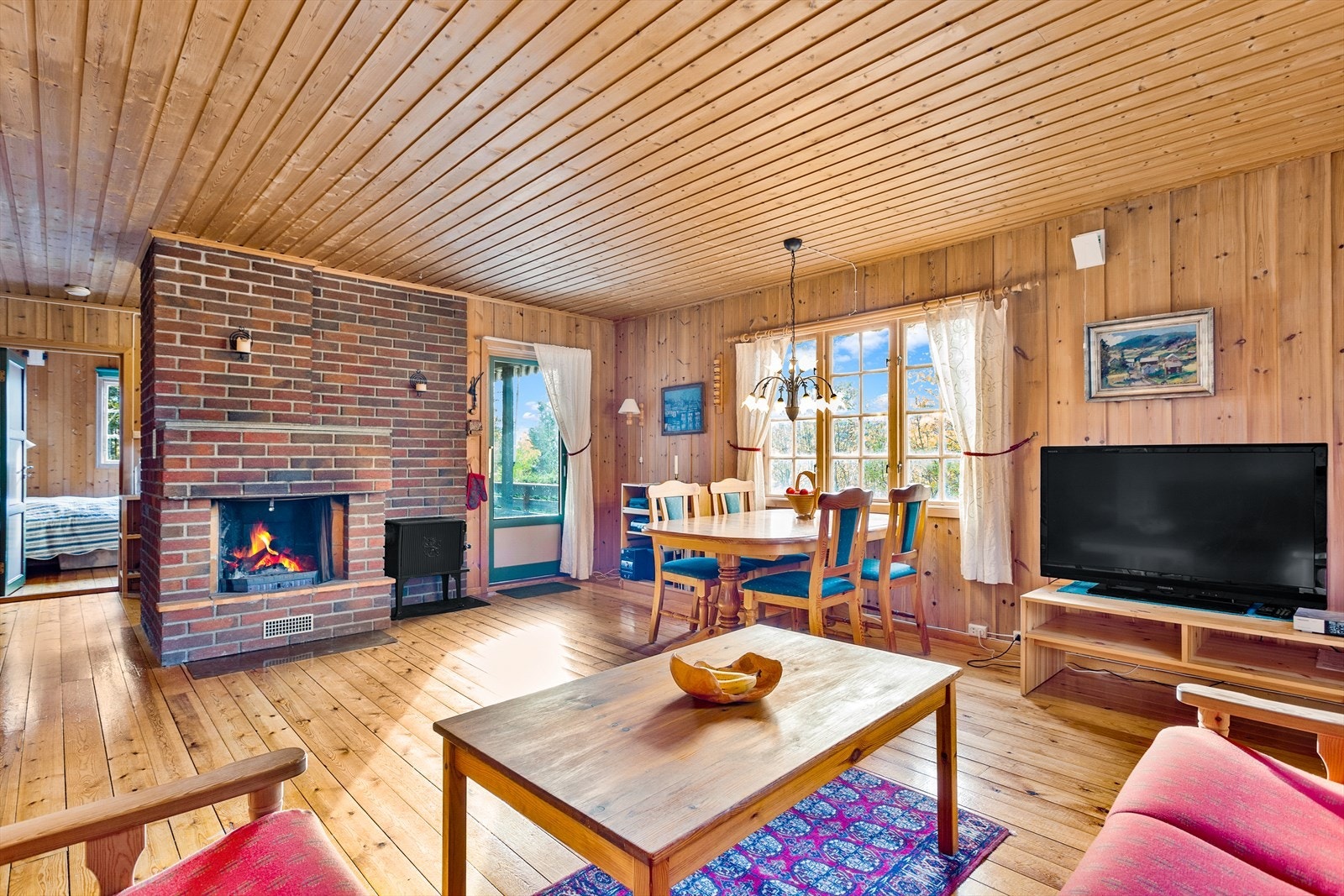 Koselig stue med peis og naturlig lys fra store vinduer Galleribilde