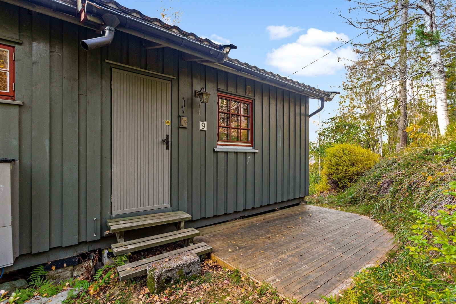 Utsiden av hytten med terrasse og naturlig skogsterreng Galleribilde