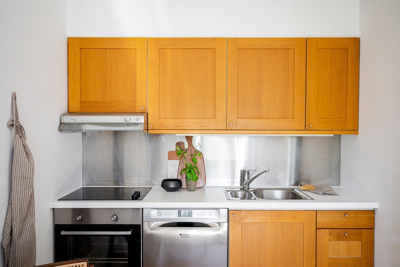 Pen og tidløs kjøkkeninnredning fra 2005 med profilerte fronter, benkeplate av laminat og backsplash belagt med stålplate. Galleribilde